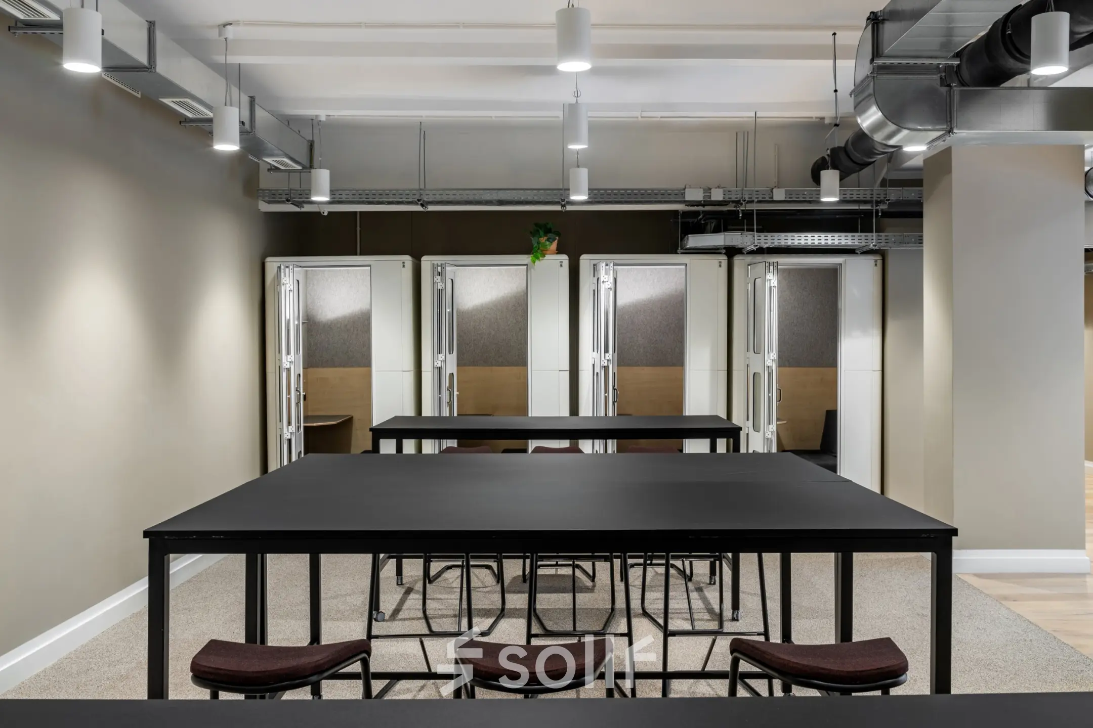 Modern office space to rent at Chausseestraße 29 in Berlin Kreuzberg, featuring sleek tables and chairs under industrial lighting.