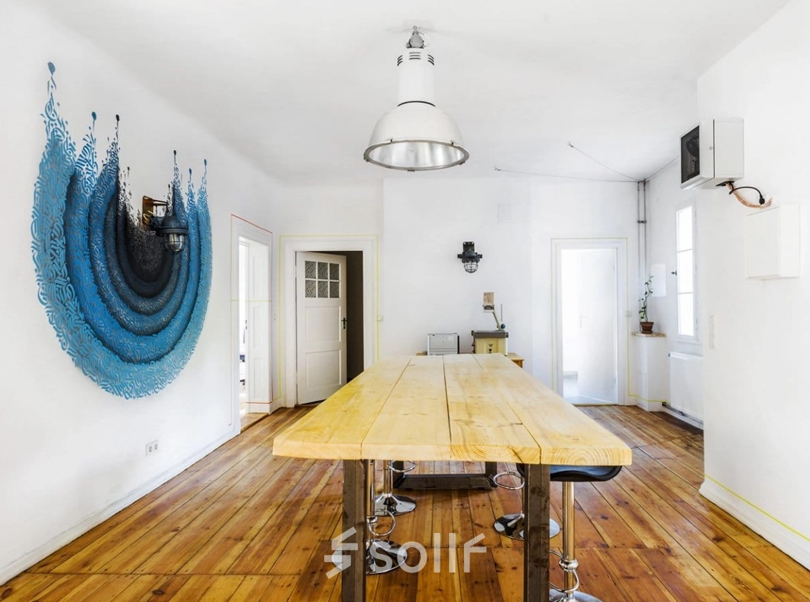 Berlin Lichtenberg office space rental at Blockdammweg 1 with a unique wall art, wooden flooring, and modern furnishings. Ideal for an office to rent with natural light and stylish decor.