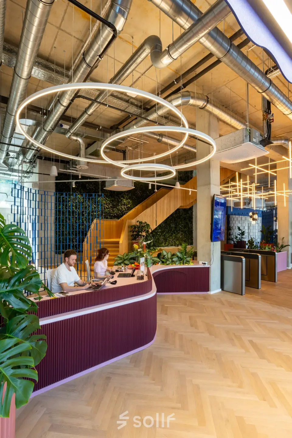 Modern reception area at Heidestraße 34, Berlin Mitte, with sleek circular lighting and a reception desk where two people are working.