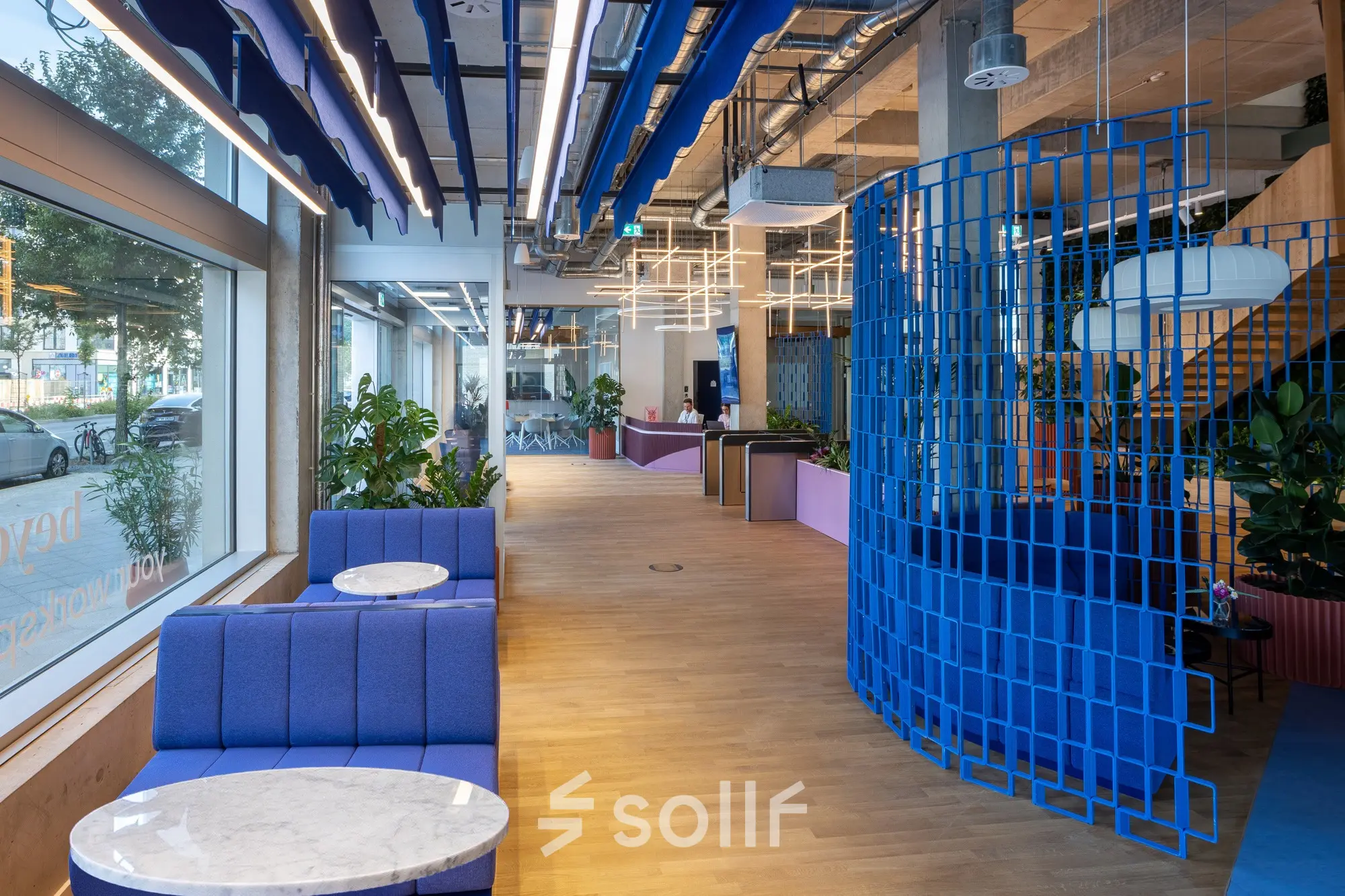 Brightly colored office space with blue seating and tables next to large windows, suitable for rent office space at Heidestraße 34, Berlin Mitte.