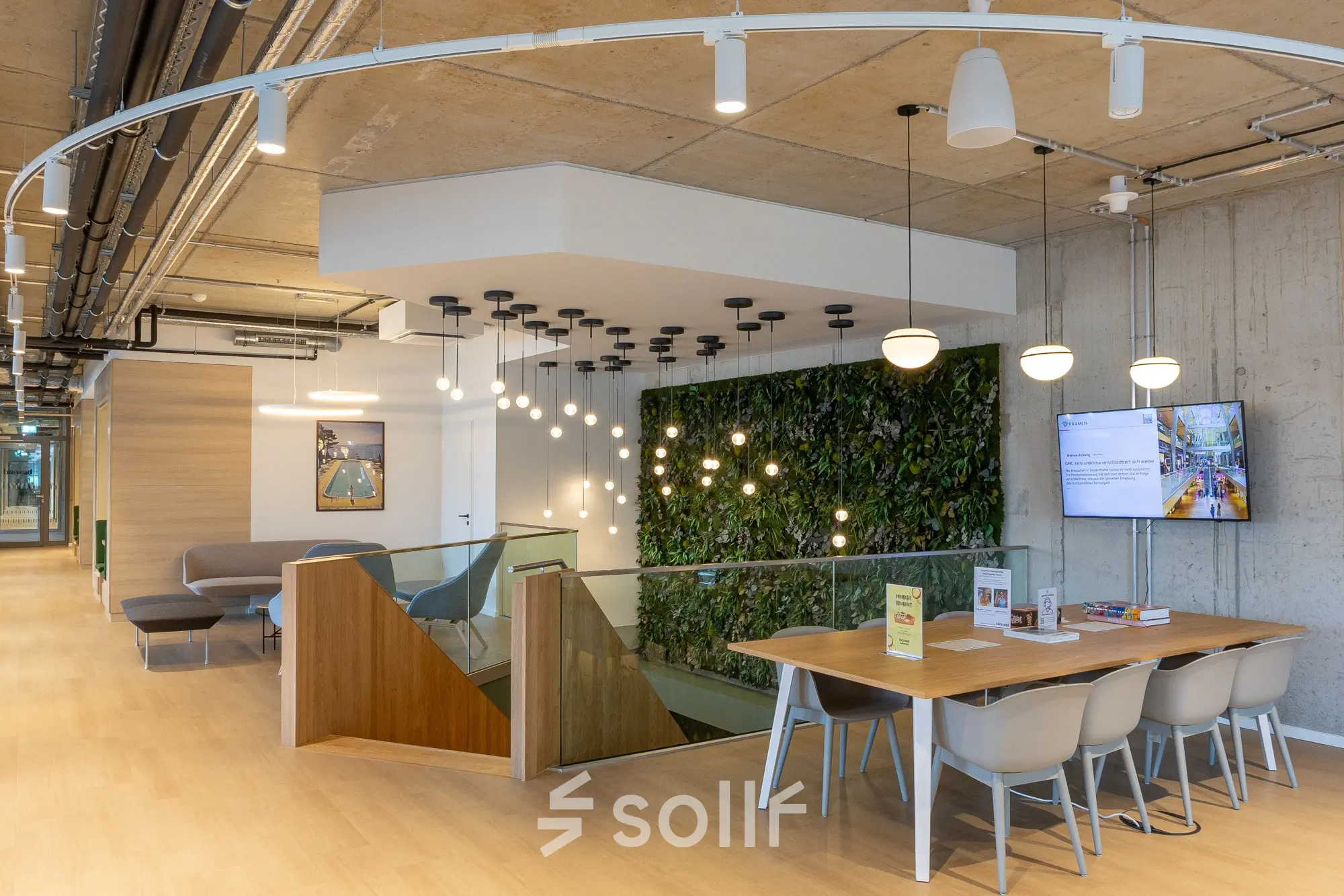 Modern workspace with a green wall, a wooden table, and seating area at Heidestraße 34, perfect for office space rental.