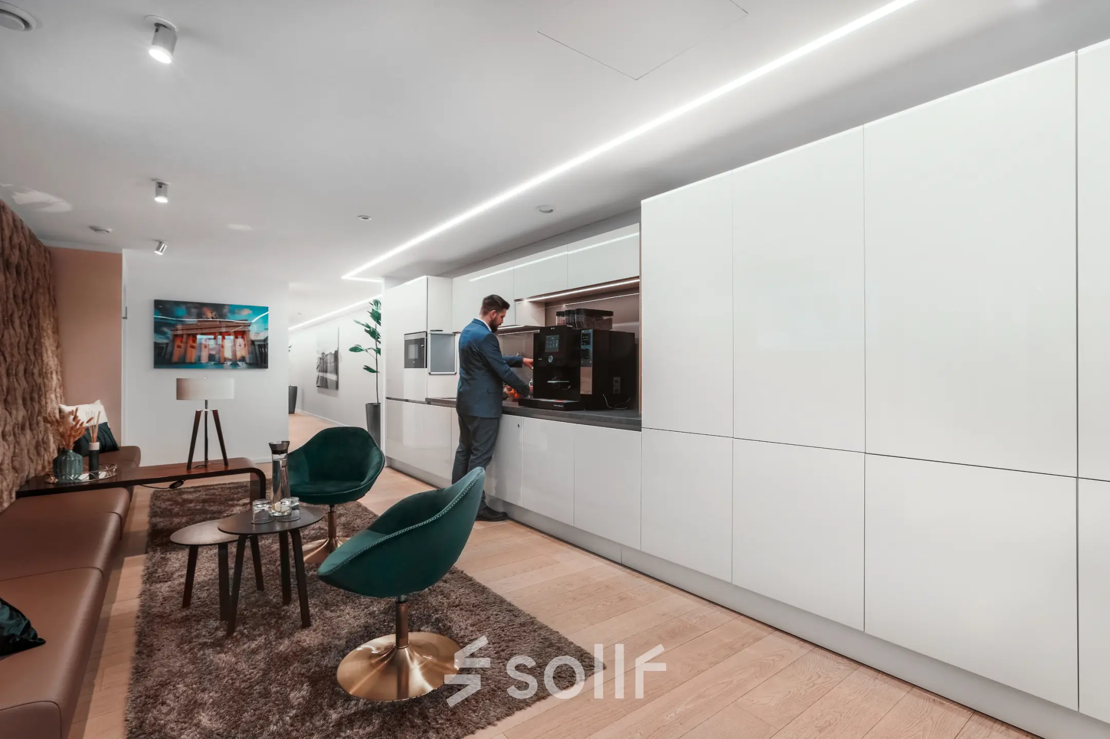 A modern, furnished office space at Pariser Platz 6a, Berlin Mitte, featuring a lounge area and a person using a coffee machine. Ideal for those looking to rent office space.