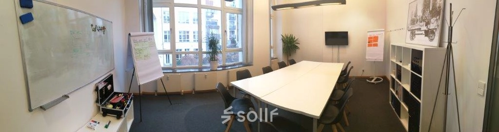 Spacious and bright conference room available for office space rental in Berlin Mitte, featuring a large table, chairs, and a whiteboard.