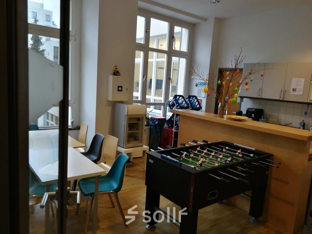 Office space rental in Berlin Mitte featuring a furnished lounge with tables, chairs, and a foosball table in a well-lit room at Zinnowitzer Straße 1.