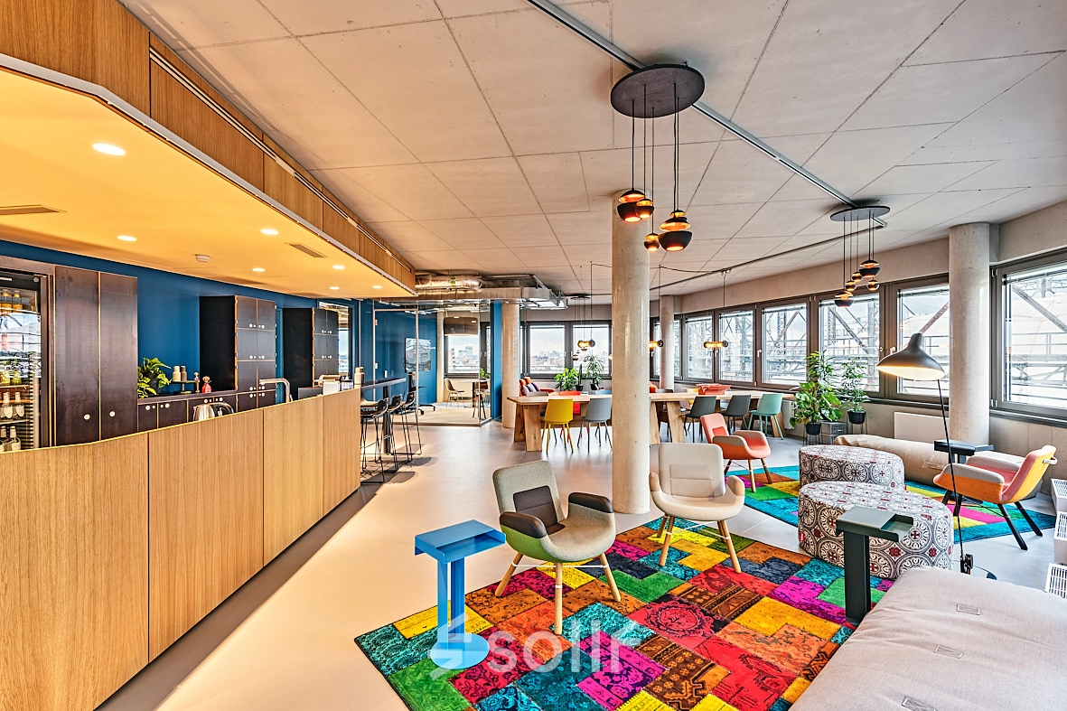 Spacious and colorful office interior on EUREF-Campus 22 in Berlin Schöneberg, featuring vibrant furnishings and ample natural light, ideal for those seeking a dynamic office space rental.