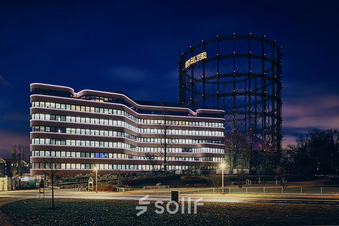 Night view of EUREF-Campus 22 in Berlin Schöneberg, showcasing modern architecture against the illuminated gasometer.