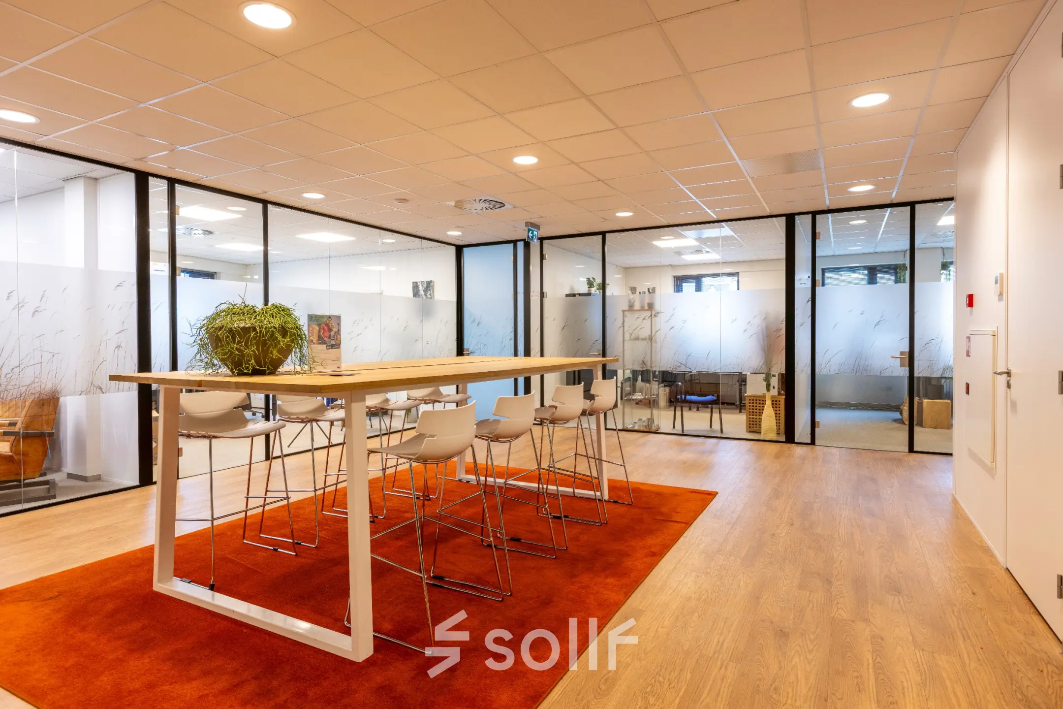 Modern office space at Marktstraat 1-7 in Bodegraven featuring a high table with stools and minimalist decor, ideal for office space rental.