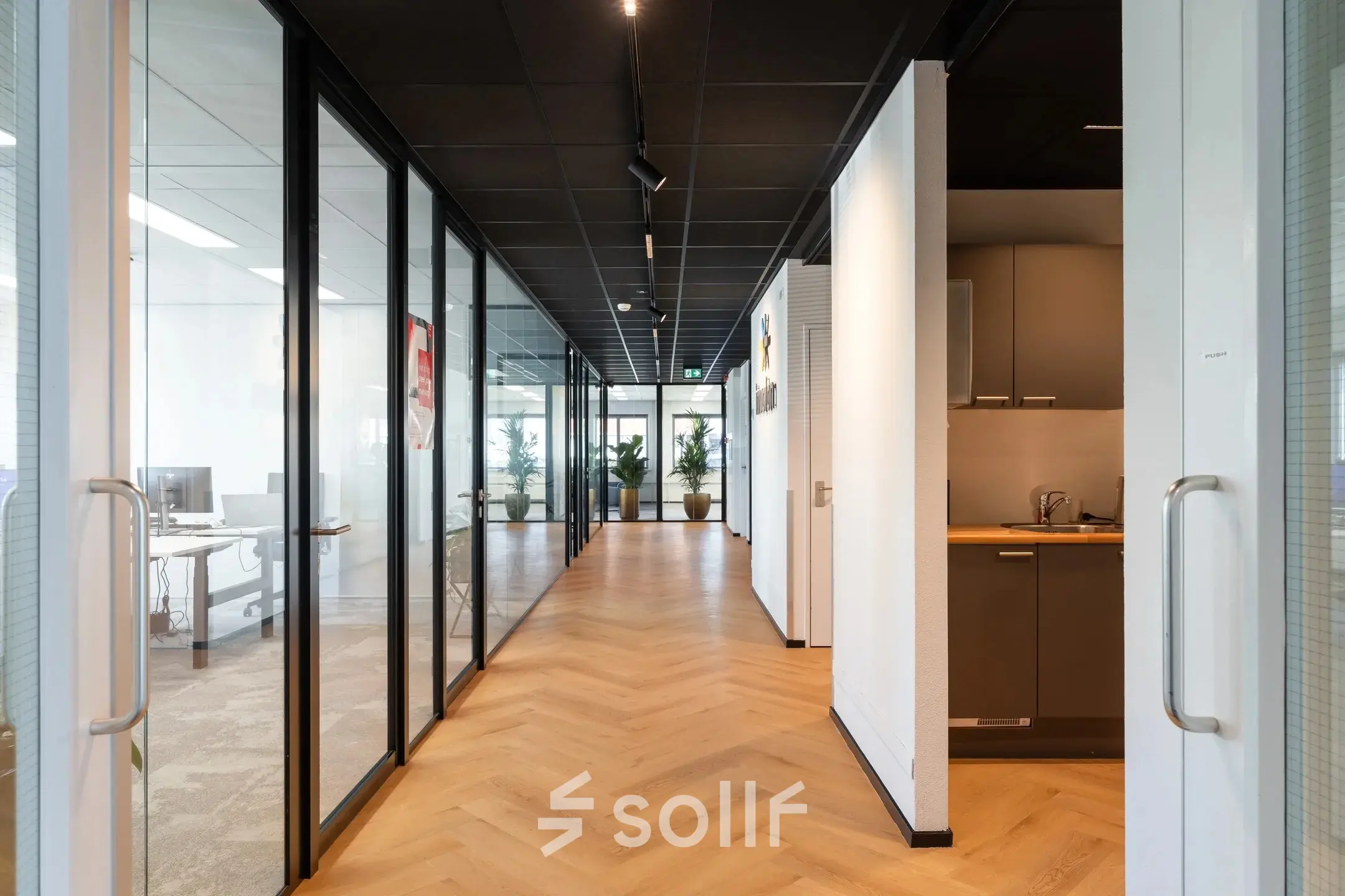 Modern office space at Tolnasingel 1-3 in Bodegraven featuring a sleek corridor with glass-walled meeting rooms on the side. Ideal for office space rental.