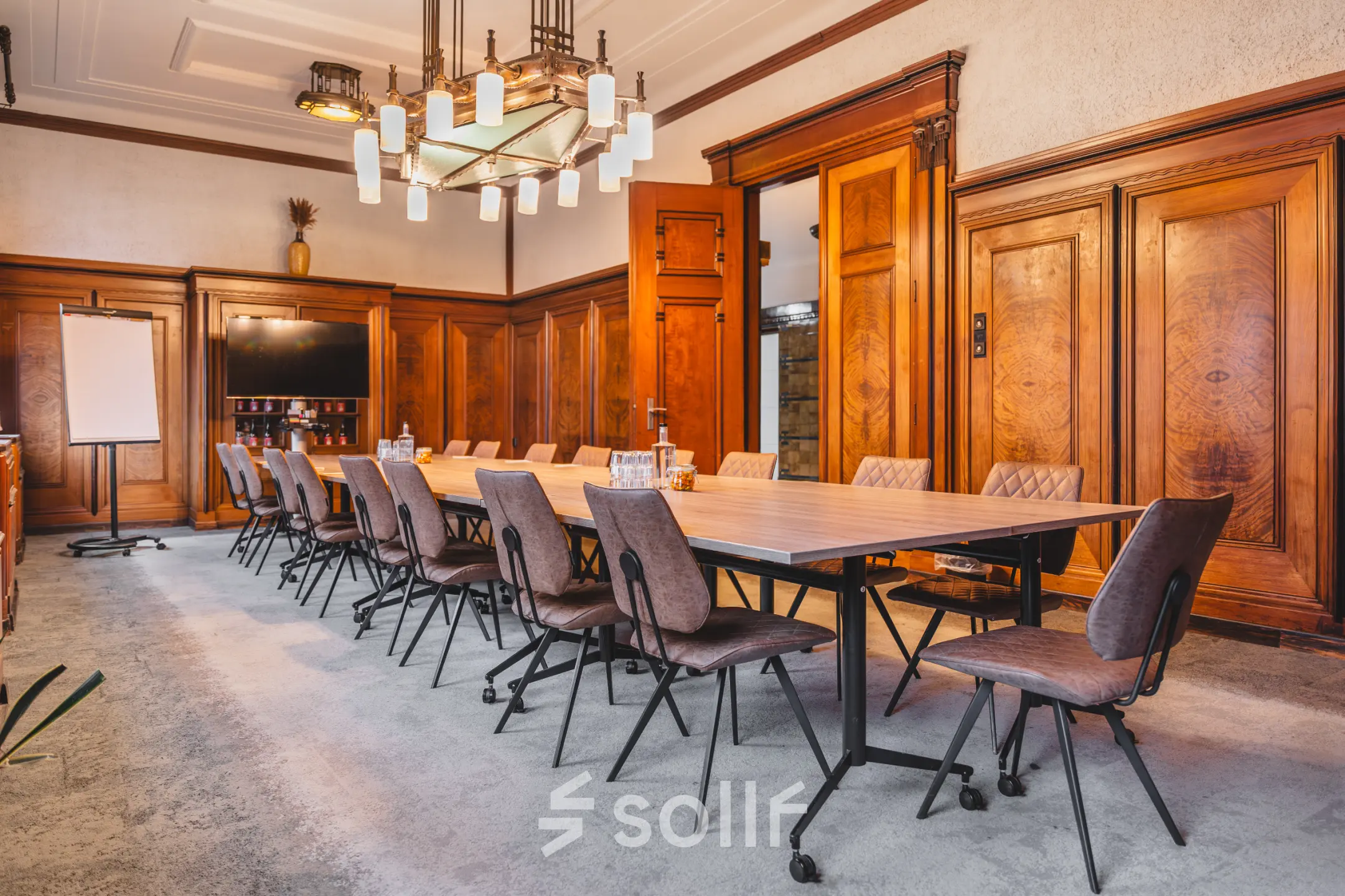 Spacious conference room at Ceresstraat 13, Breda Centrum-Station, featuring a long table with chairs, wood-paneled walls, and a TV. Ideal office space rental for meetings or presentations.