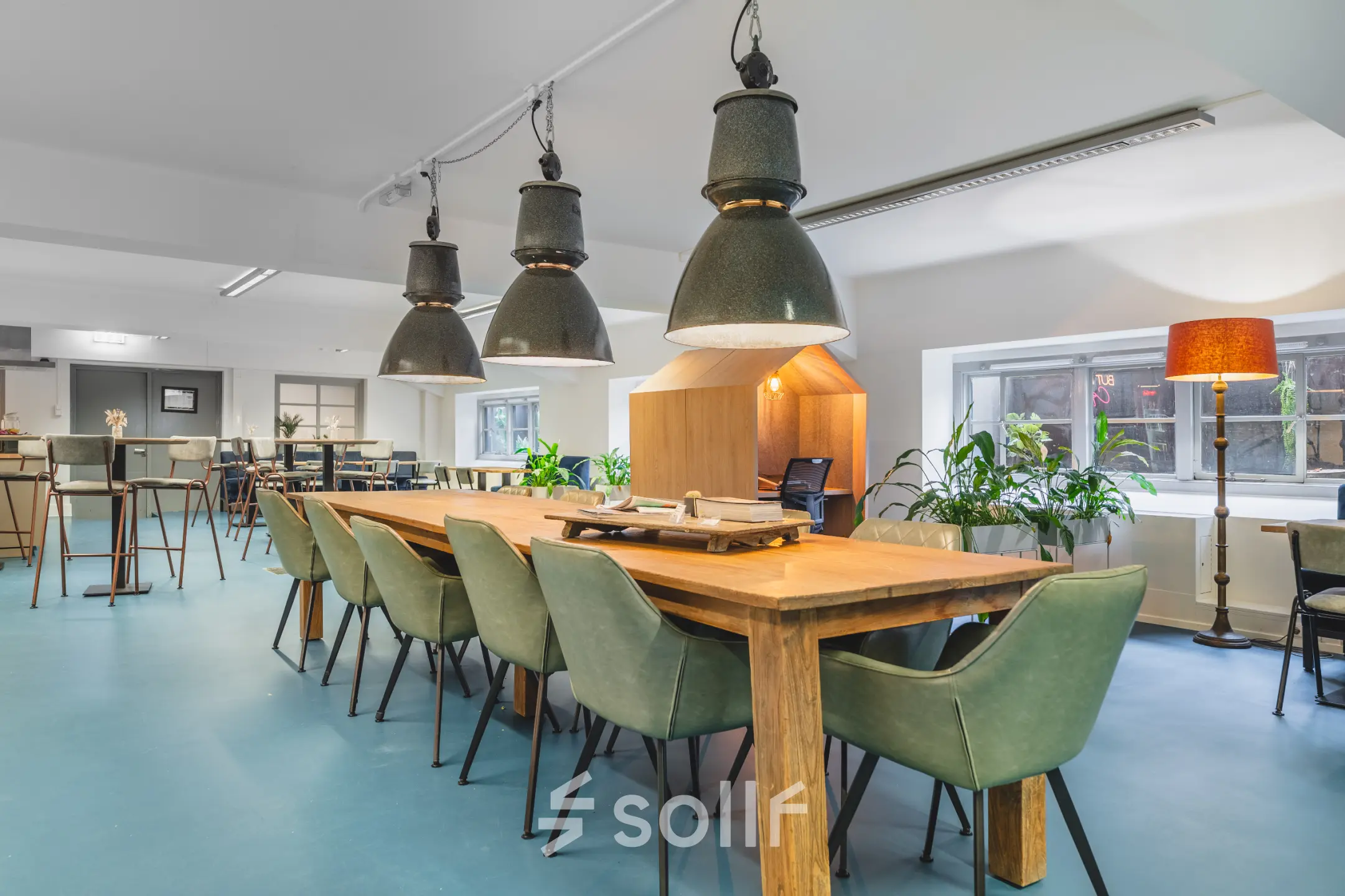 Spacious furnished workspace with wooden tables, stylish green chairs, and large ceiling lights, ideal for office space rental at Ceresstraat 13 in Breda Centrum-Station.