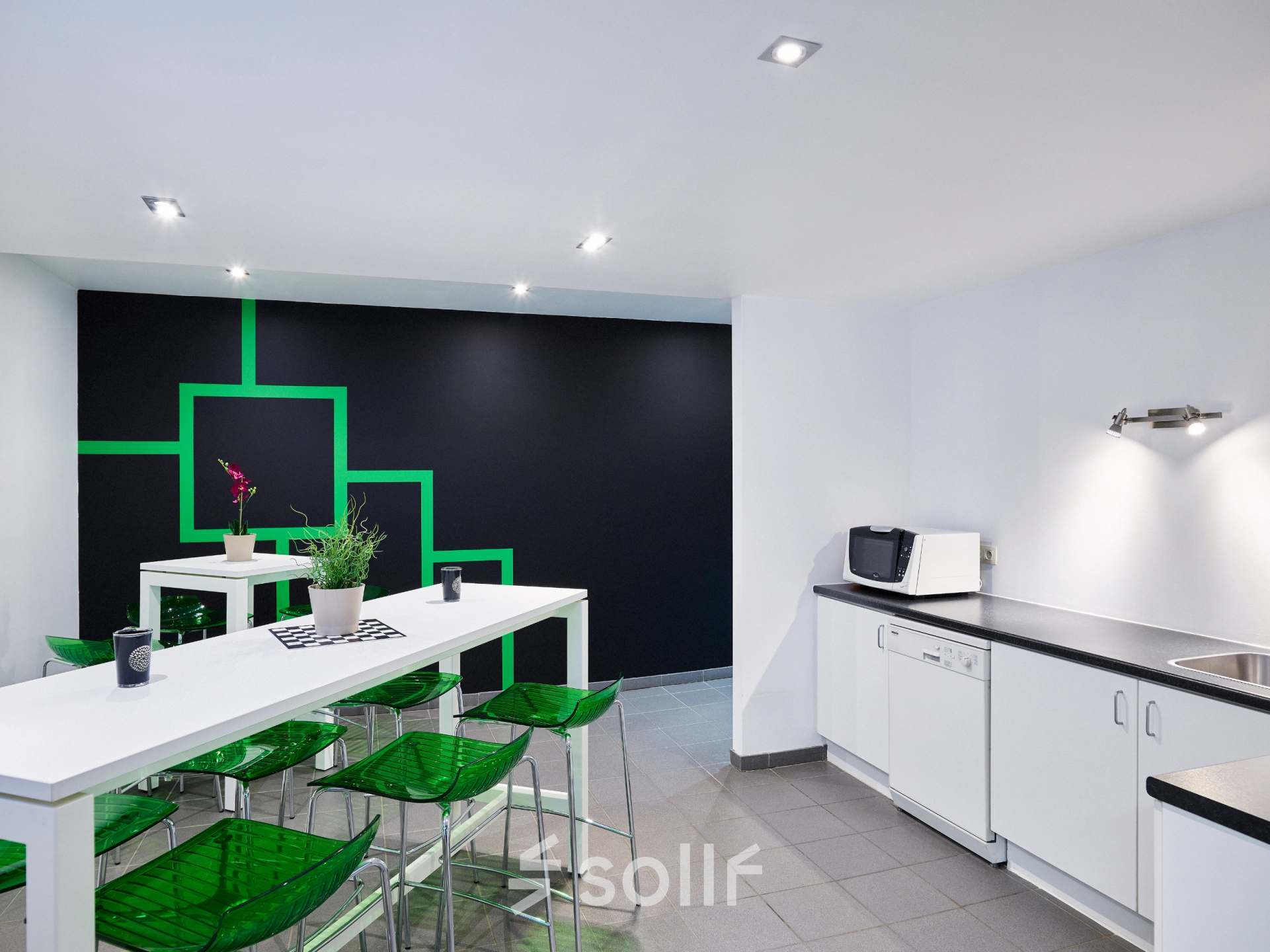 Bright office space rental with a modern kitchenette and vibrant green seating, ideal for breaks and informal meetings at Brussels Airport. Available to rent office space at Leuvensesteenweg 613.