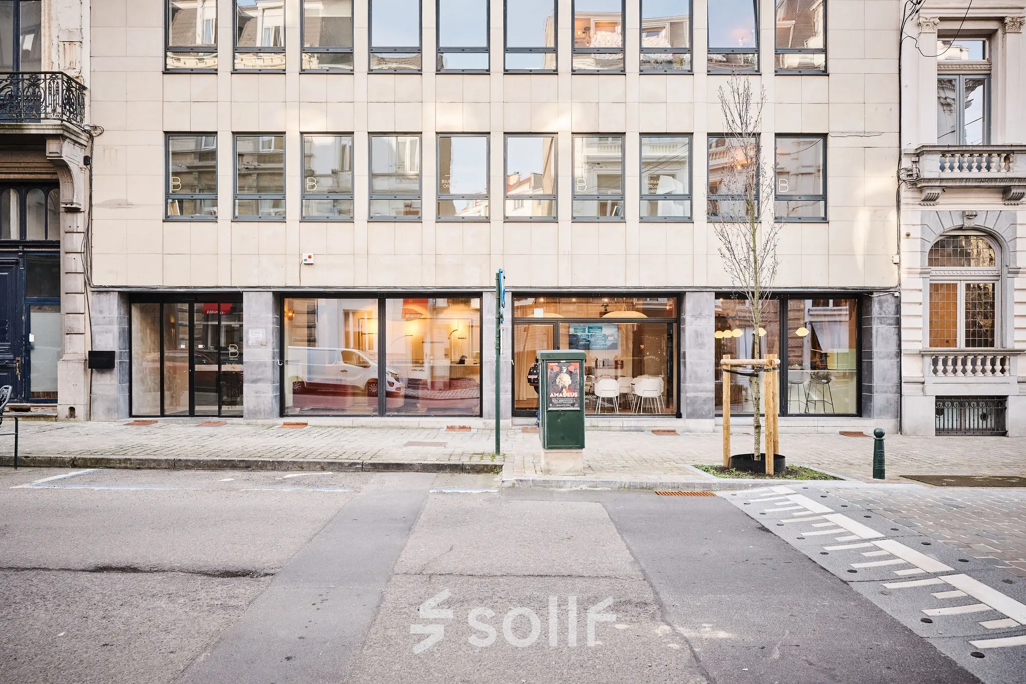 Exterior view of an office building on Rue du Congres 37, featuring large windows with glimpses of the interior, ideal for office space rental in Brussels Center.