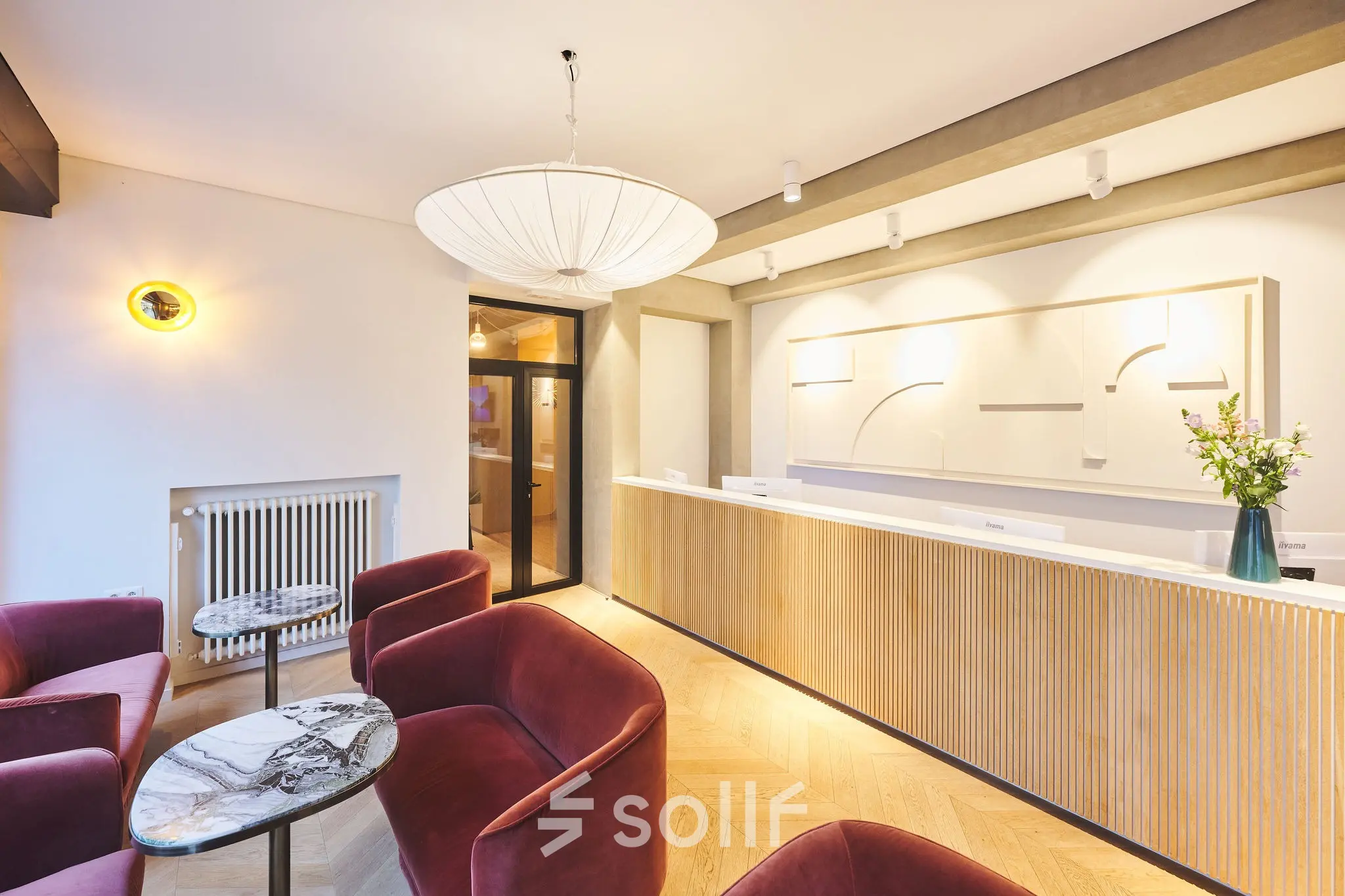 Modern reception area with a wooden desk and stylish red chairs, ideal for renting office space in Brussels Center.