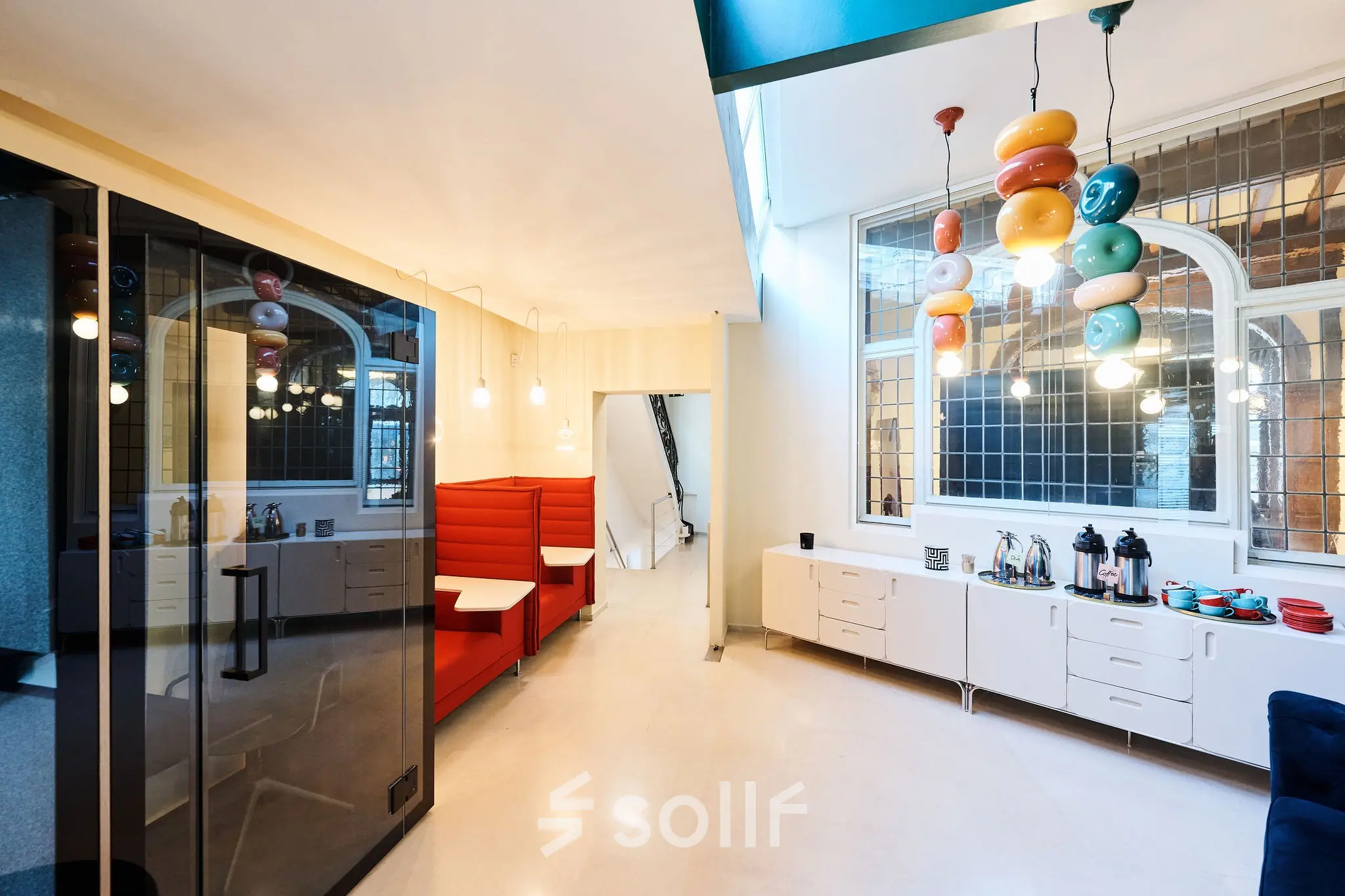 Bright office space with modern furnishings and playful lighting in Rue du Congres 37, Brussels Center, available for rent. Includes workspaces and a coffee station.