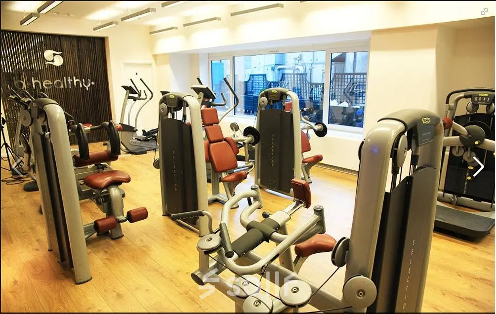 Modern gym facility available for rent office space at Rue Joseph Stevens 7, Brussels Center, equipped with fitness machines and large windows for natural light.