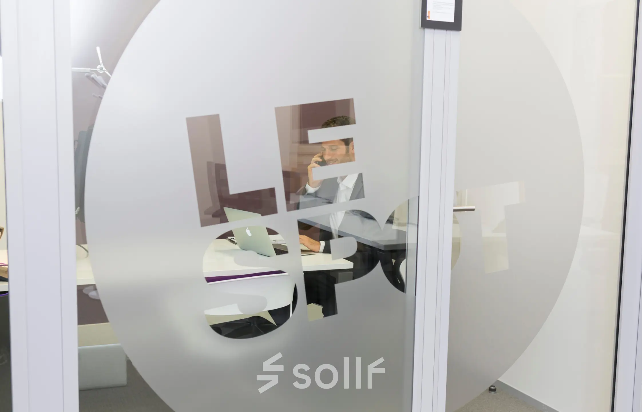 Interior view of an office space rental on Rue Joseph Stevens 7, Brussels Center, featuring a person working at a desk with a laptop.