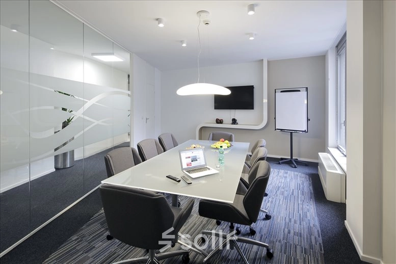 Modern office space with a glass wall, meeting table, chairs, TV, and flipchart in Avenue Louise, Brussels. Perfect for office space rental.