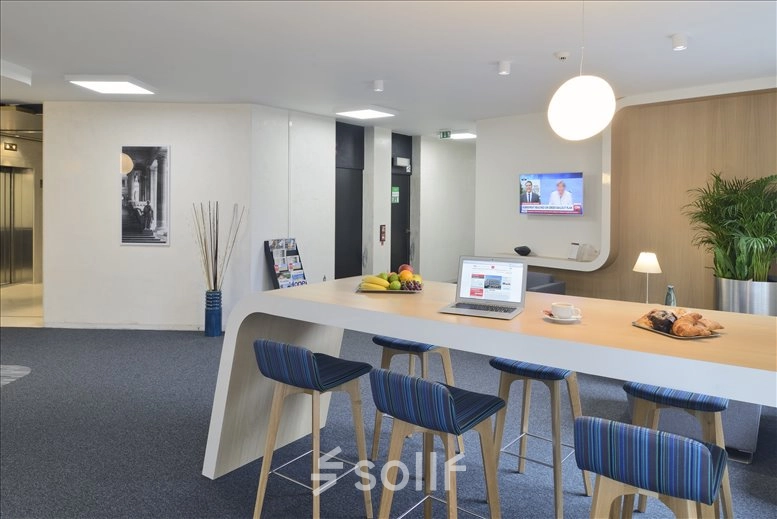 A modern office space with a high countertop and stools, featuring a laptop and assorted snacks. Ideal for rent as a workspace in Brussels.