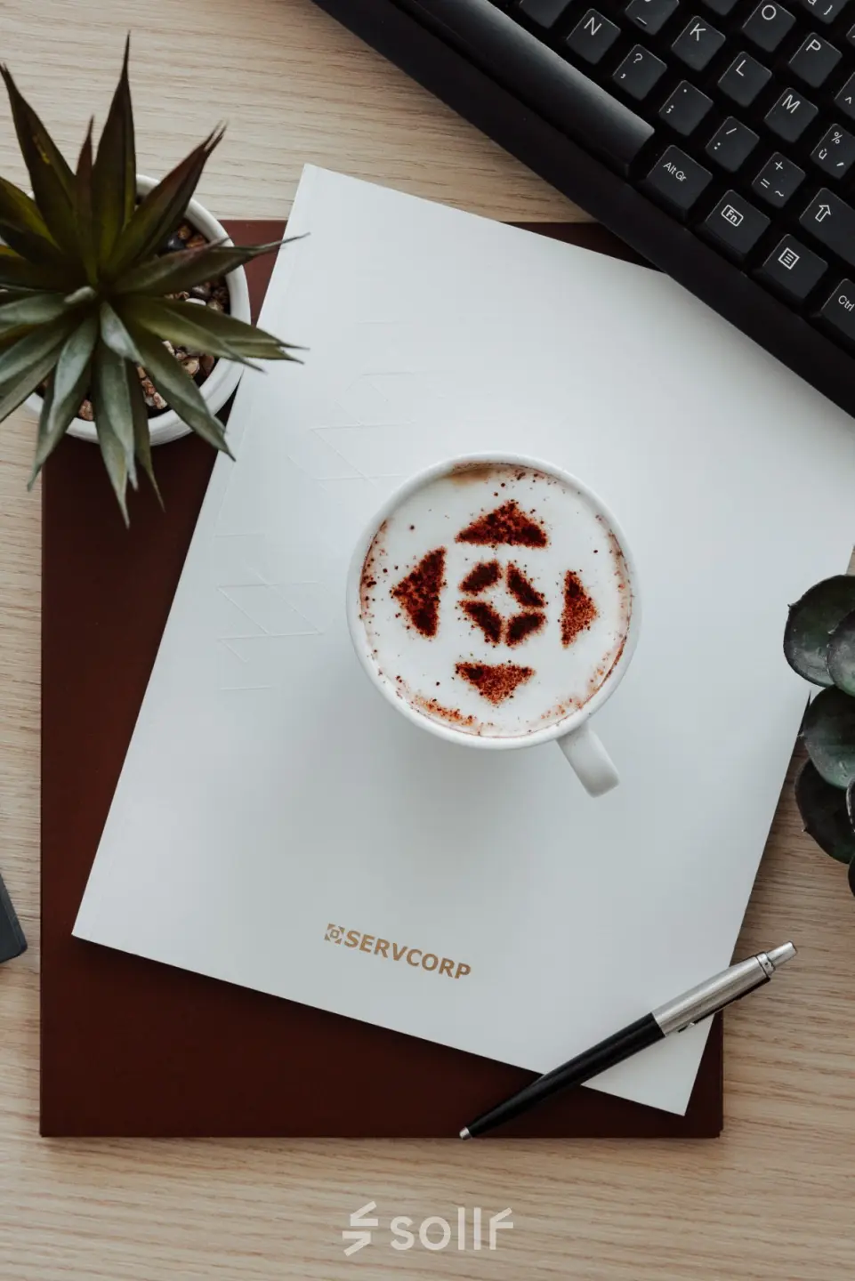 A stylish office desk with a keyboard, coffee cup, notebook, pen, and plants, ideal for office space rental.