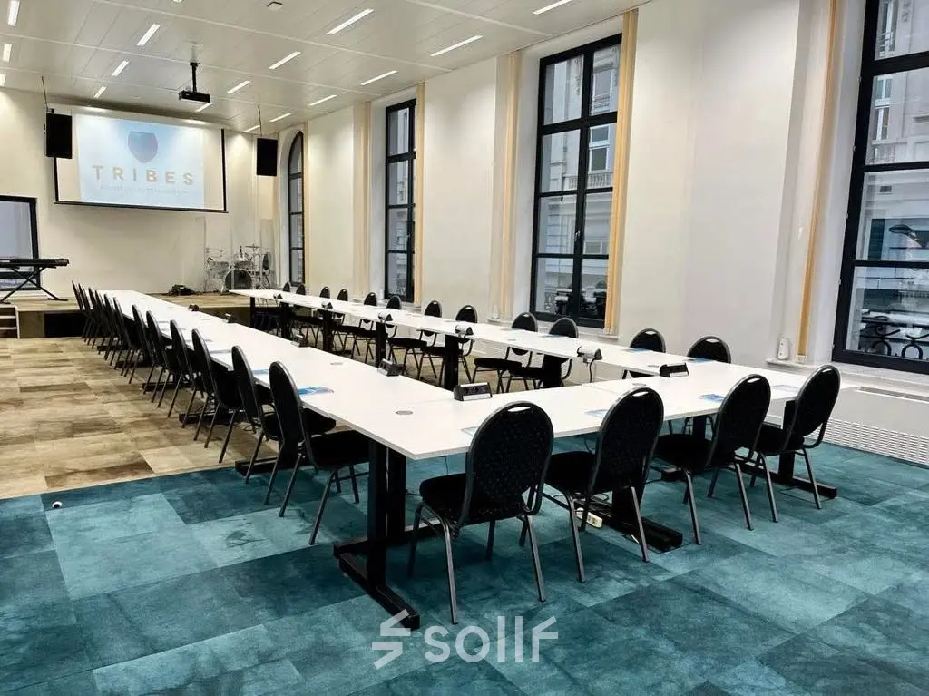 Spacious, well-lit office to rent on Rue des Colonies 56, Brussels European District, featuring a long conference table with multiple chairs.