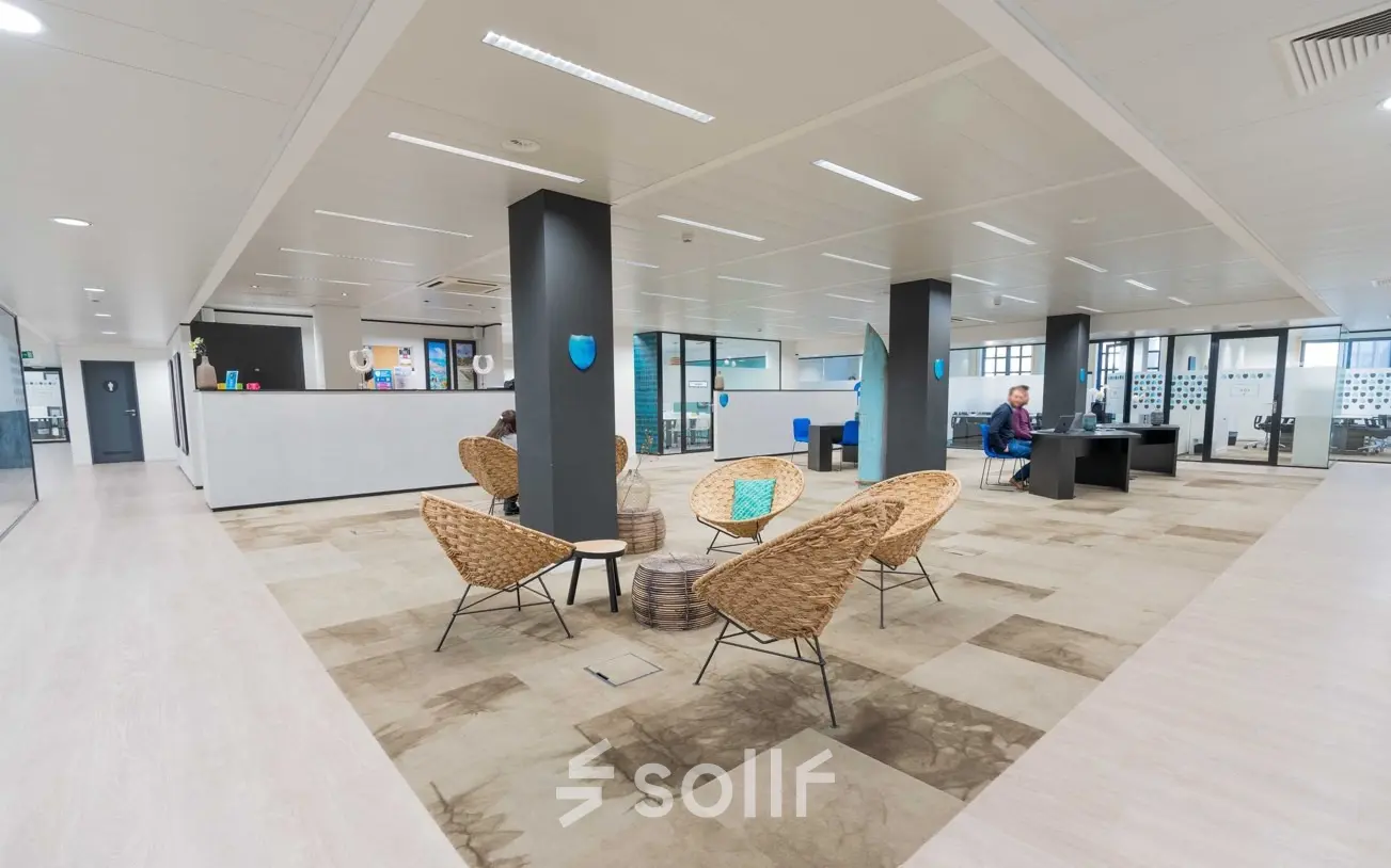 Spacious office with modern furnishings and individuals engaged in work, located at Rue des Colonies 56, ideal for office space rental in Brussels European District.