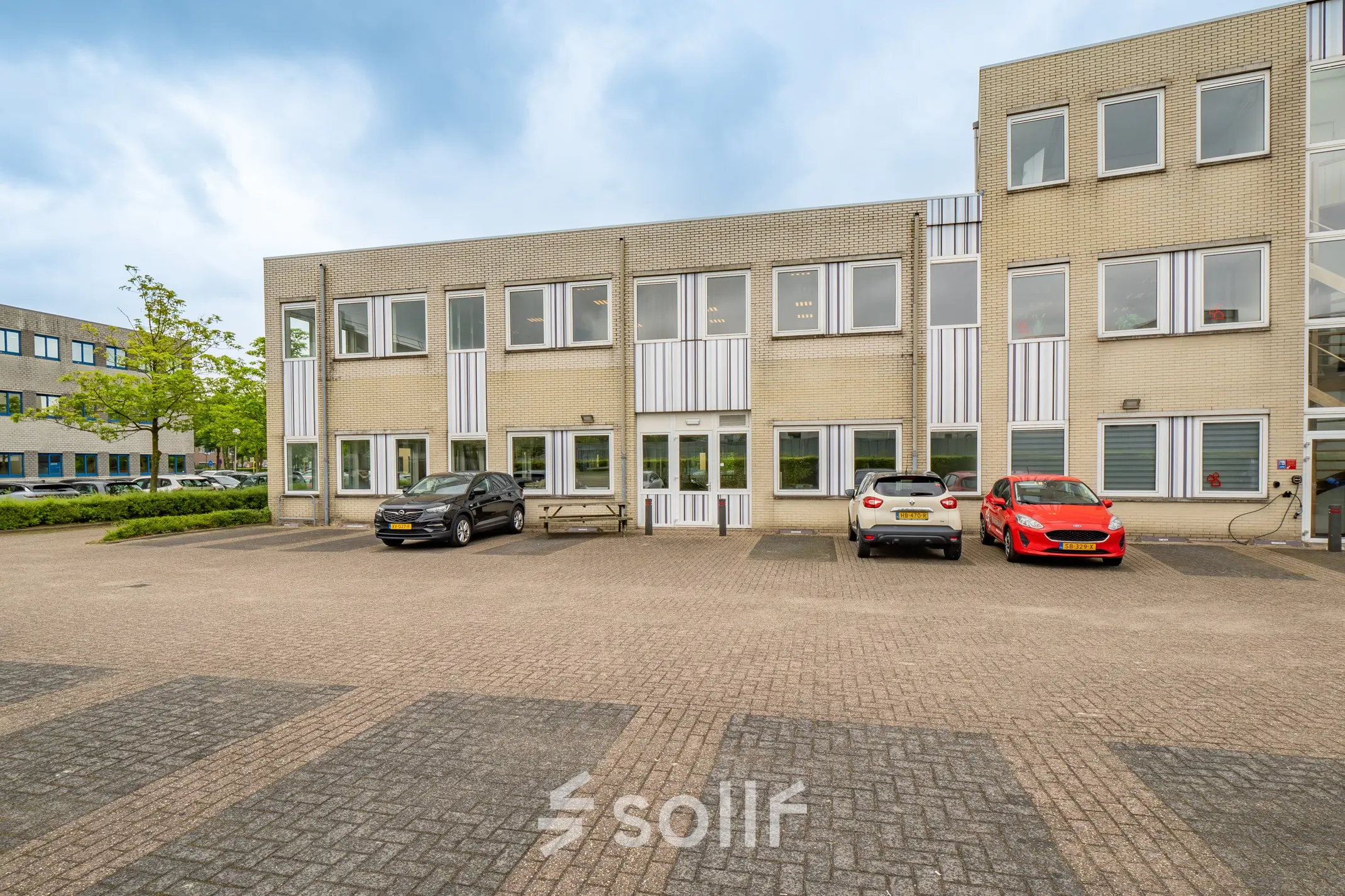 Exterior view of office space for rent at Regulierenring 2, Bunnik, showing a two-story building with parking area.