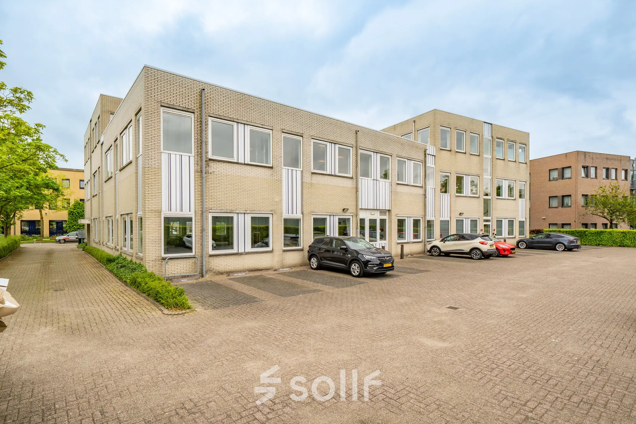 Exterior view of a commercial building at Regulierenring 2, Bunnik, showcasing parking spaces available for office space rental.