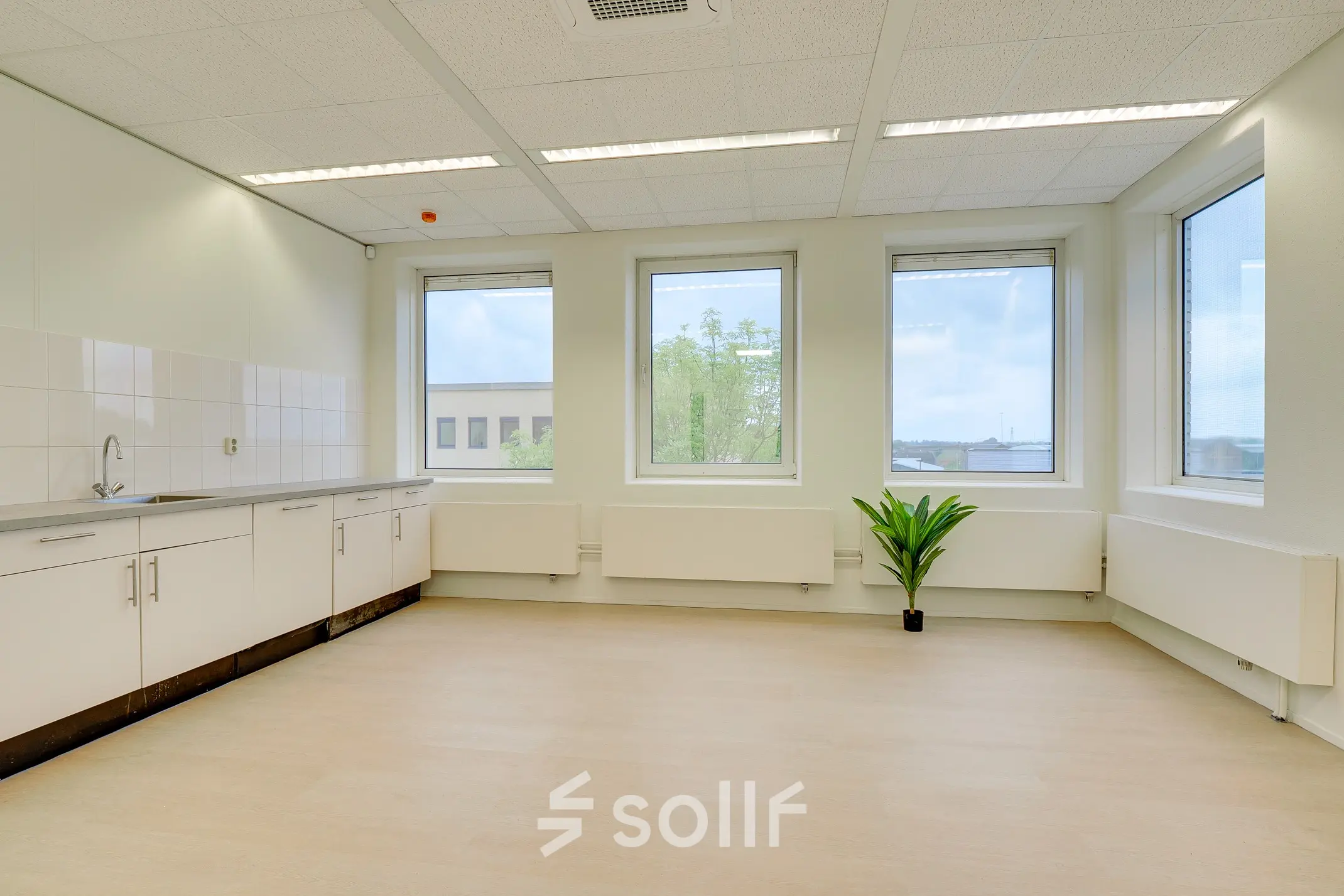 Available office space for rent at Regulierenring 2, Bunnik, featuring large windows and a kitchenette area, ideal for creating a comfortable workspace.