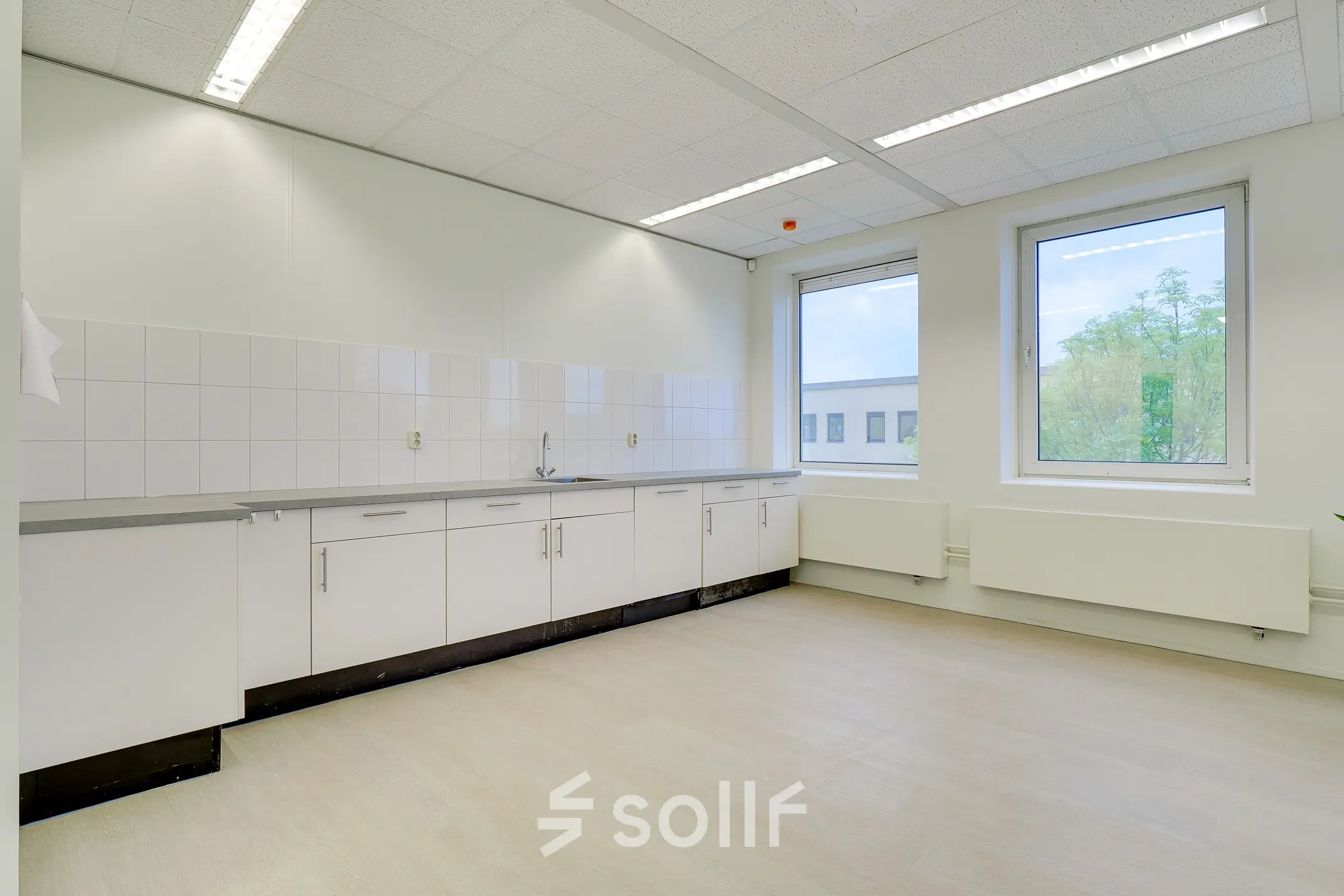 Interior view of a tidy kitchenette with countertops and cabinets at an office to rent in Bunnik.