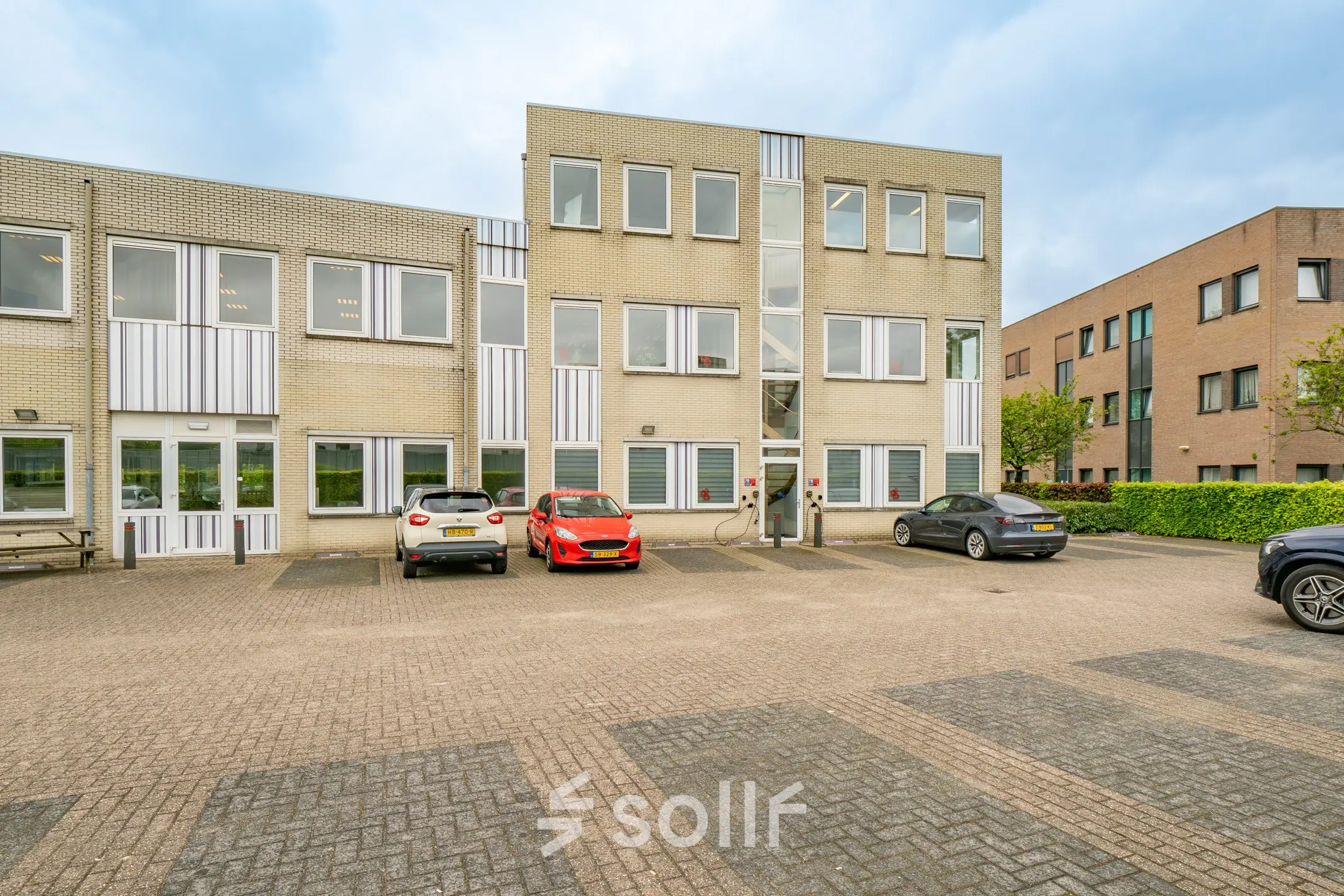 Exterior view of office building at Regulierenring 2, Bunnik, with parked cars and available office space to rent.