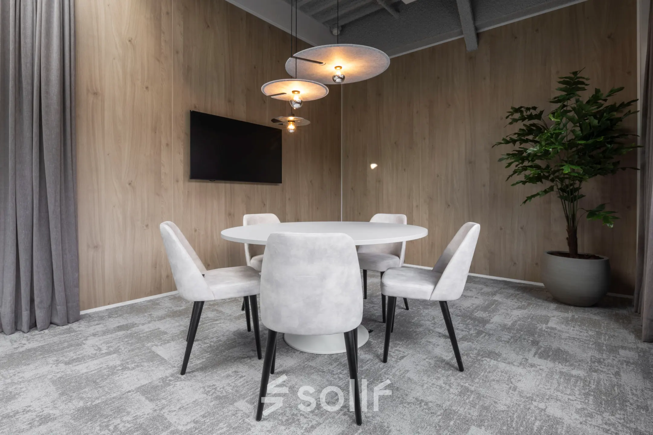 Stylish office interior at Essebaan 63, Capelle aan den IJssel, featuring a round table, chairs, and a wall-mounted TV, ideal for workspace rental.