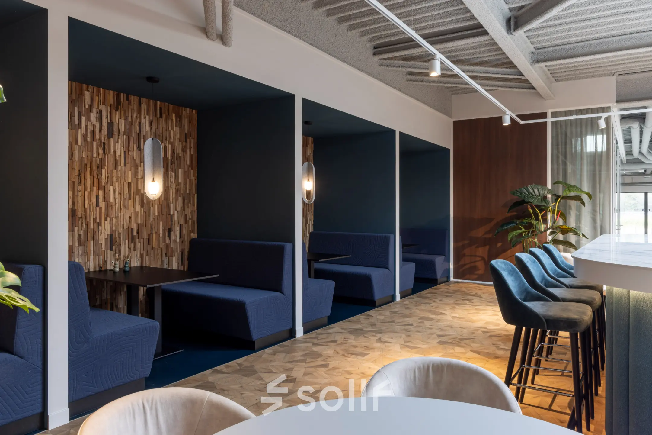 Stylish office lounge with blue booth seating, bar stools, and modern decor at Essebaan 63, Capelle aan den IJssel, ideal for office space rental.