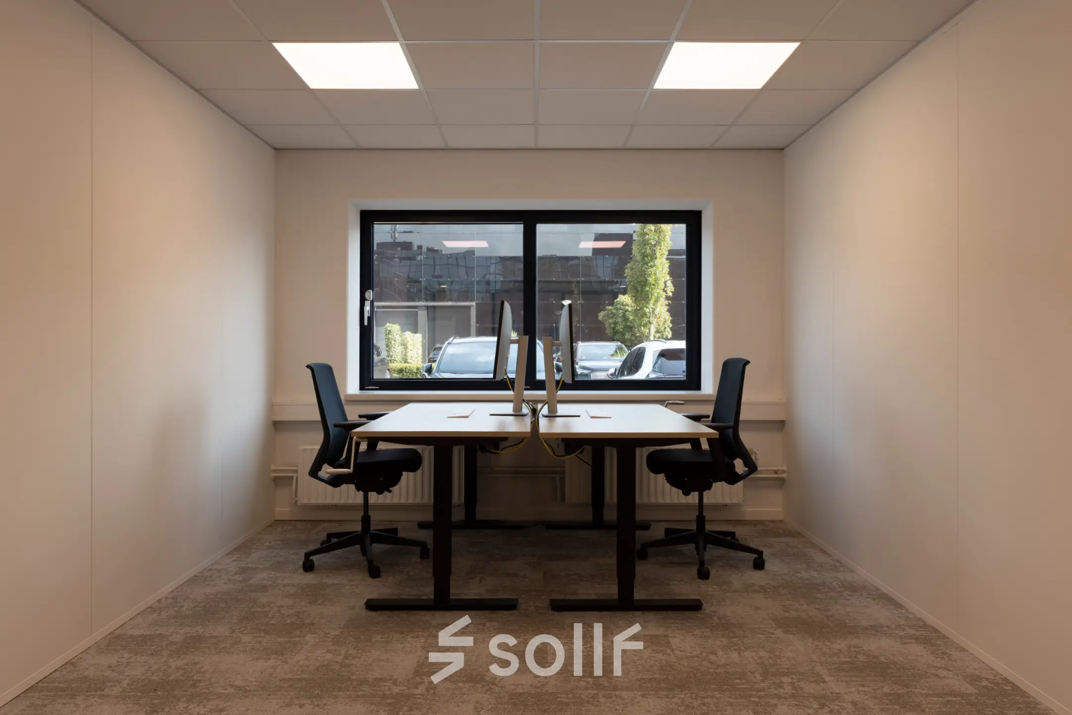 A modern office space for rent at Essebaan 63, Capelle aan den IJssel, featuring two desks with chairs and a large window providing natural light.