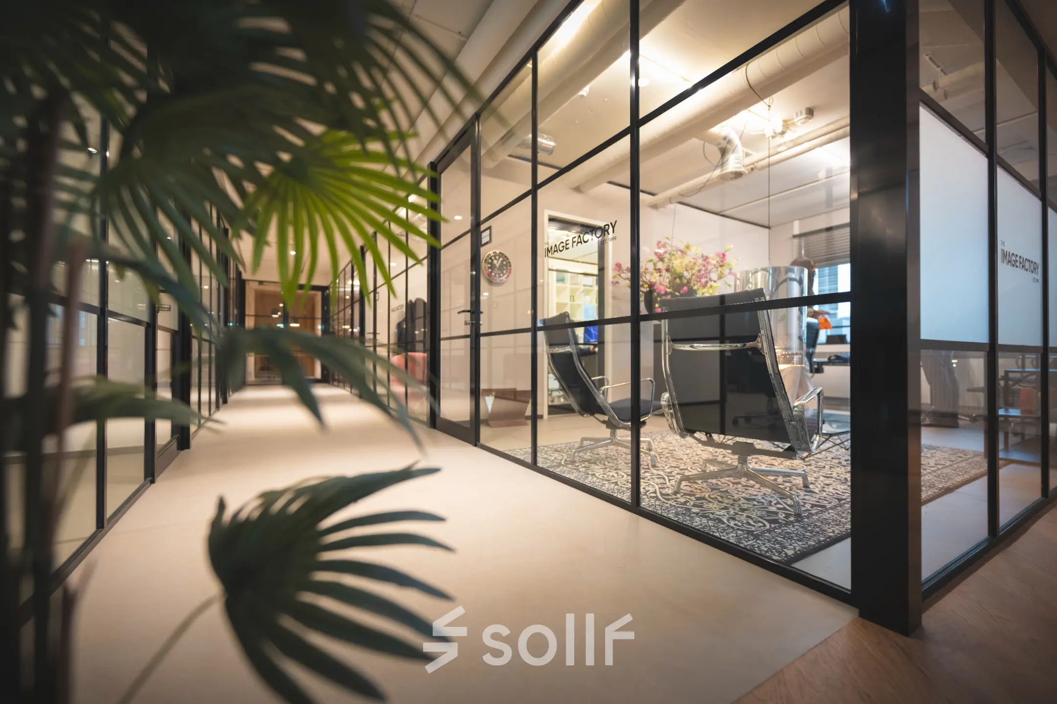 Modern office interior at Rietbaan 2-12 with glass partitions, stylish chairs, and a decorative rug, perfect for office space rental in Capelle aan den IJssel.