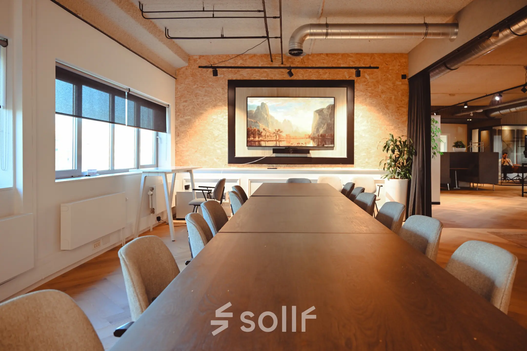Spacious meeting room with a long wooden table, chairs, and a large framed artwork on the wall, available for office space rental at Rivium Quadrant 75.