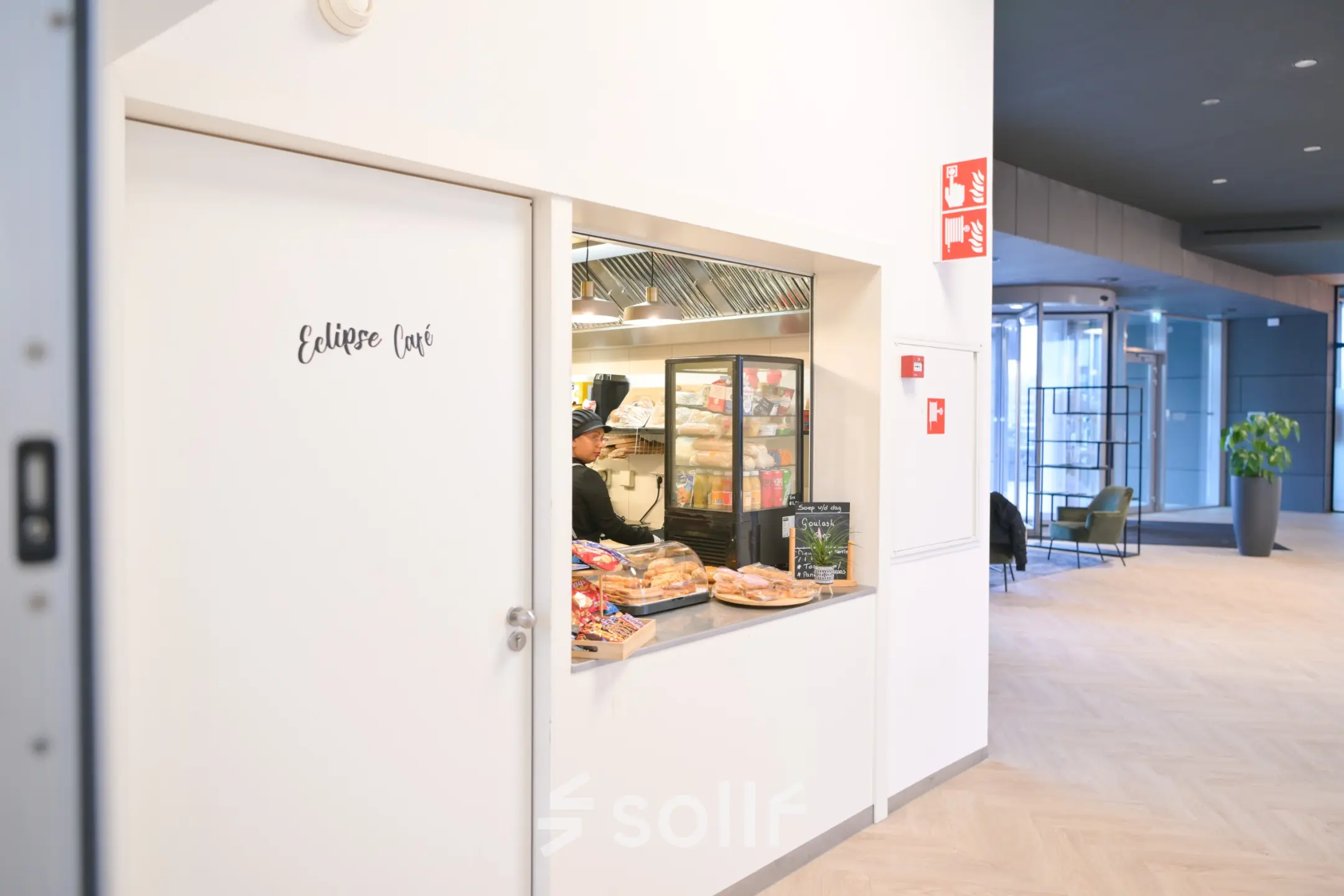 Entrance area at Rivium Quadrant 75, Capelle aan den IJssel featuring a café window with a selection of pastries, hinting at rentable office space options.