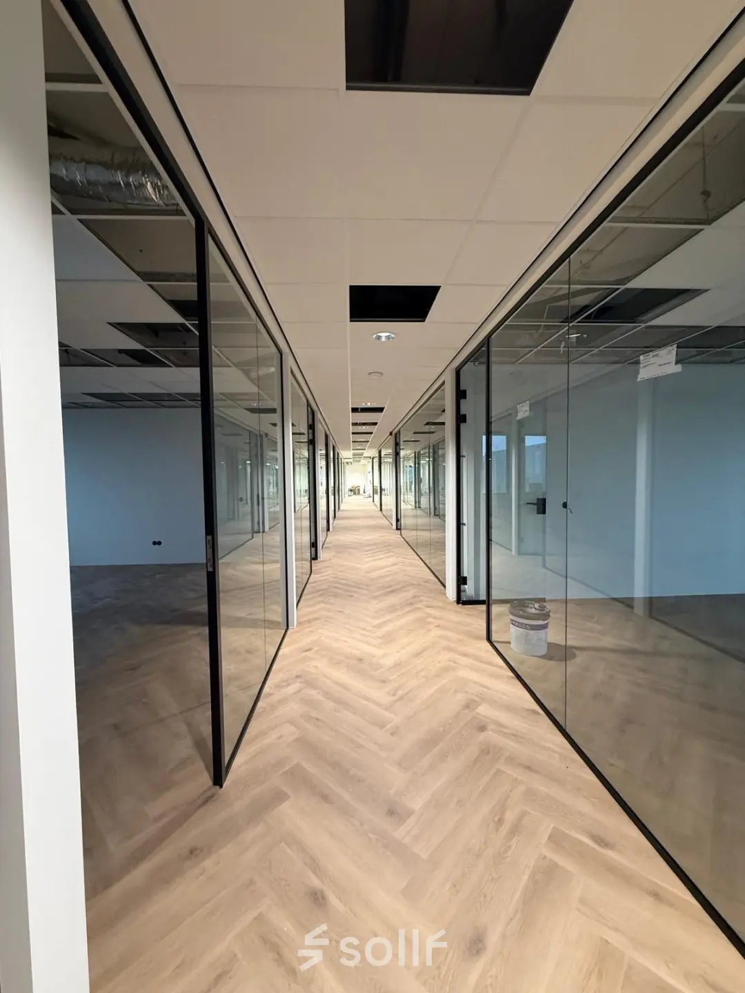 Interior view of unfurnished office space at Vlierbaan 20 in Capelle aan den IJssel, with glass-walled rooms and a wooden floor, ideal for office space rental.