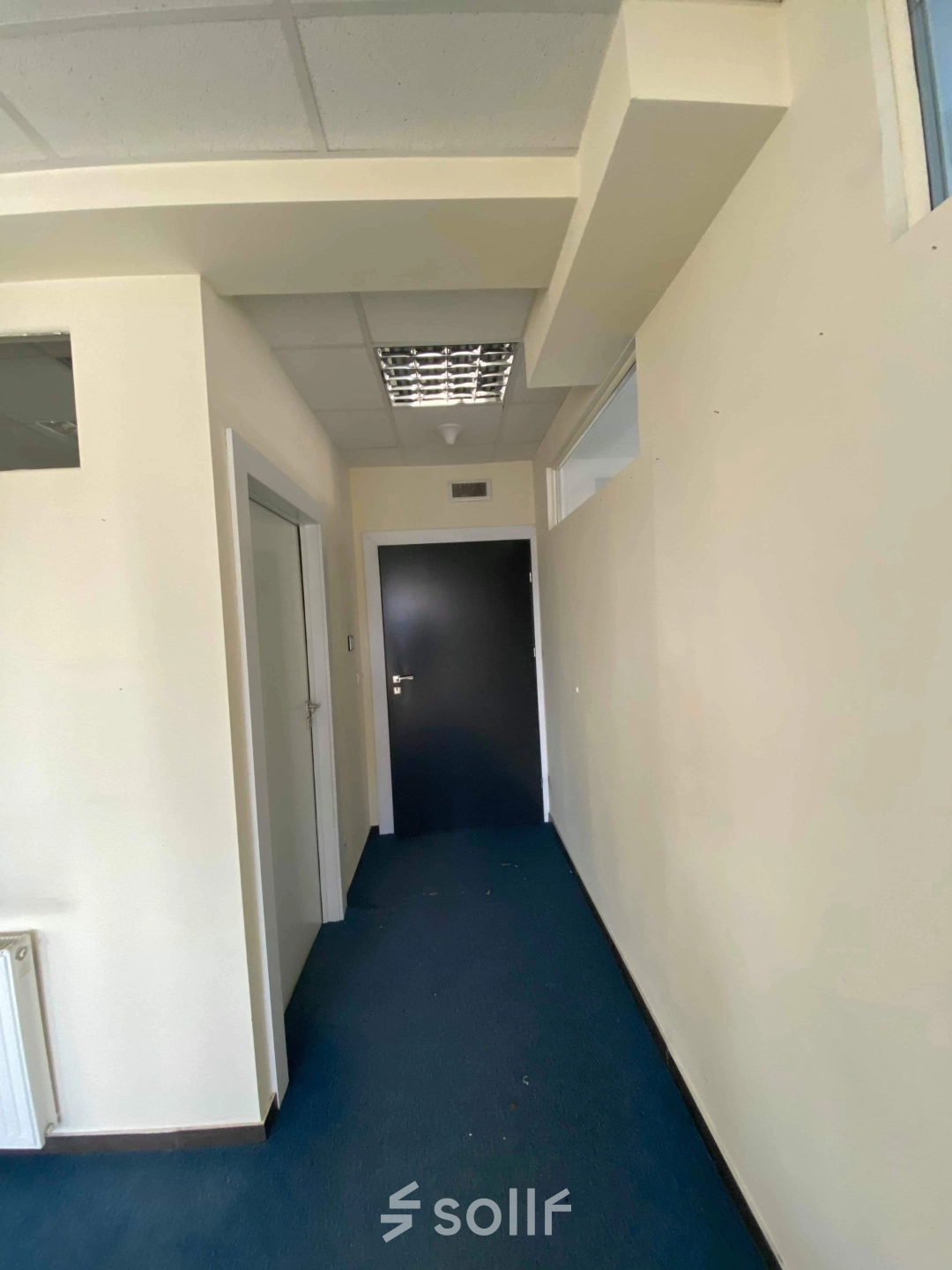 Hallway in an office space available for rent at Marcika 27, Cracow Łagiewniki Borek Fałęcki, featuring blue carpet and neutral walls.