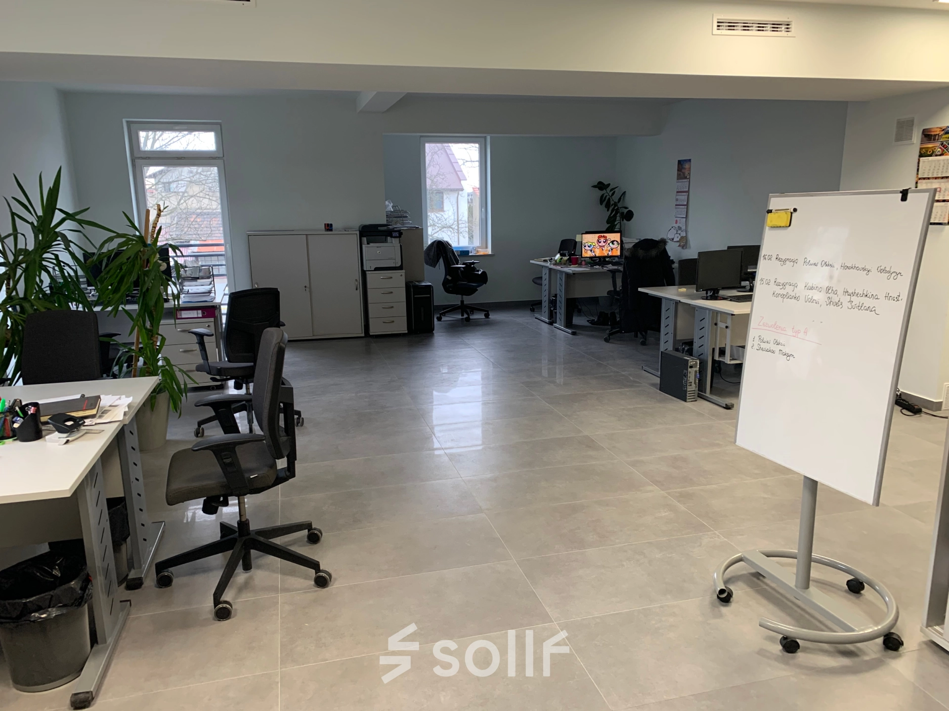 Furnished office space rental at Jastrzębia 24 in Cracow Podgorze Duchackie, featuring desks, chairs, and a whiteboard, available for rent. Bright workspaces with windows and indoor plants.