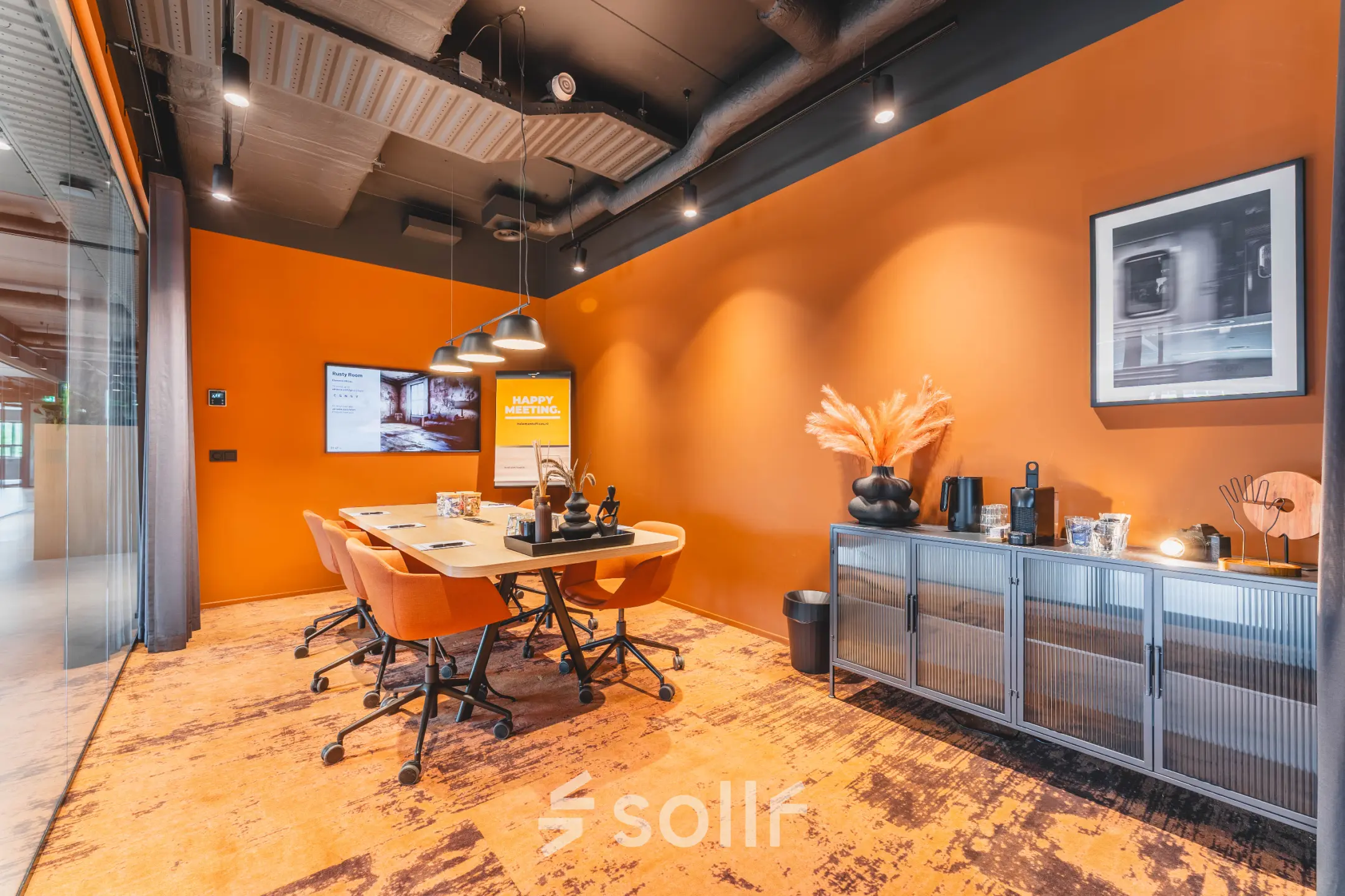 Modern office space with bold orange walls, a large table, and chairs, ideal for office space rental at Rijnzathe 12, De Meern.