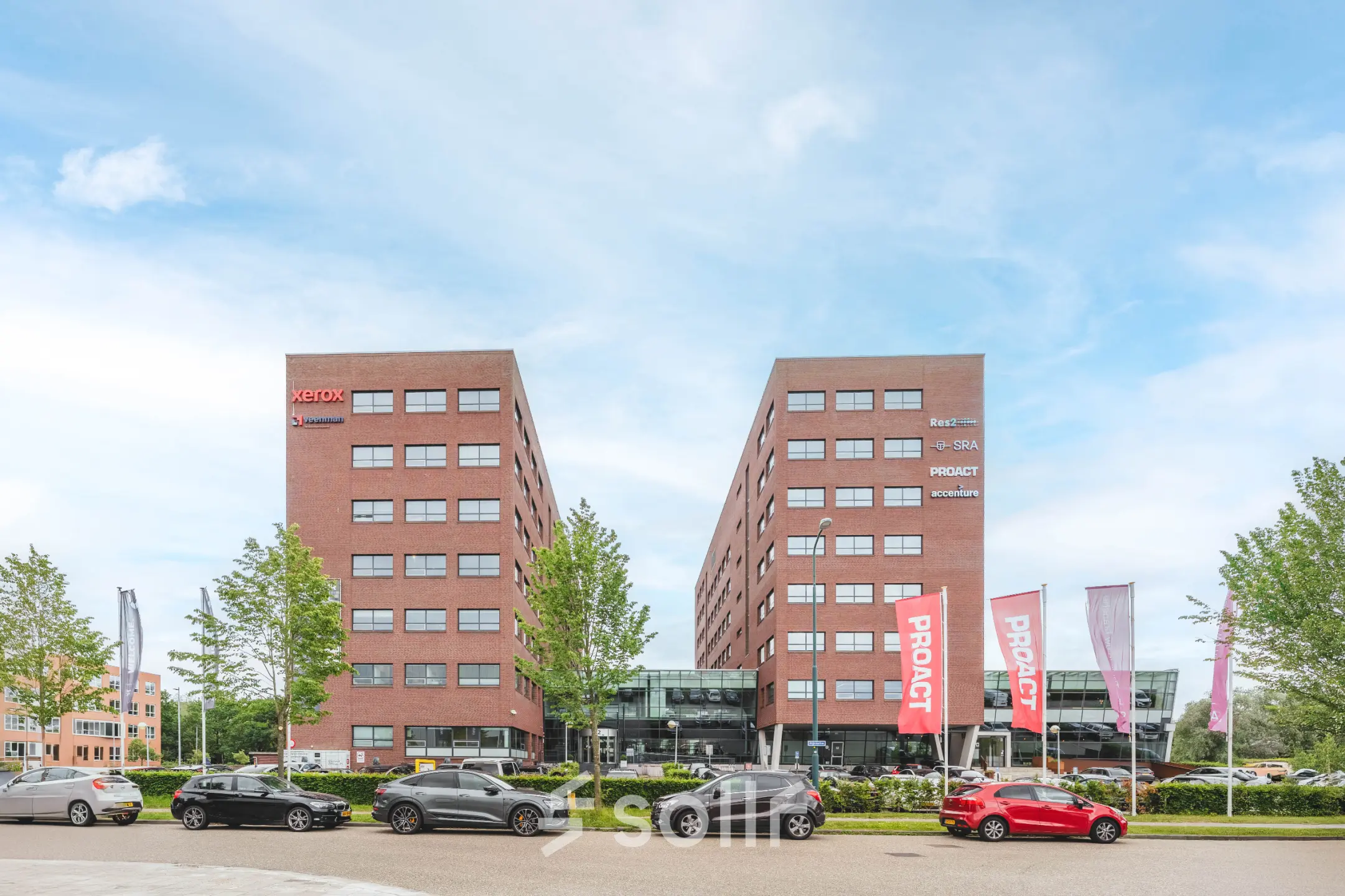 Exterior view of Rijnzathe 12 in De Meern featuring a modern office complex with multiple parked cars in the foreground.