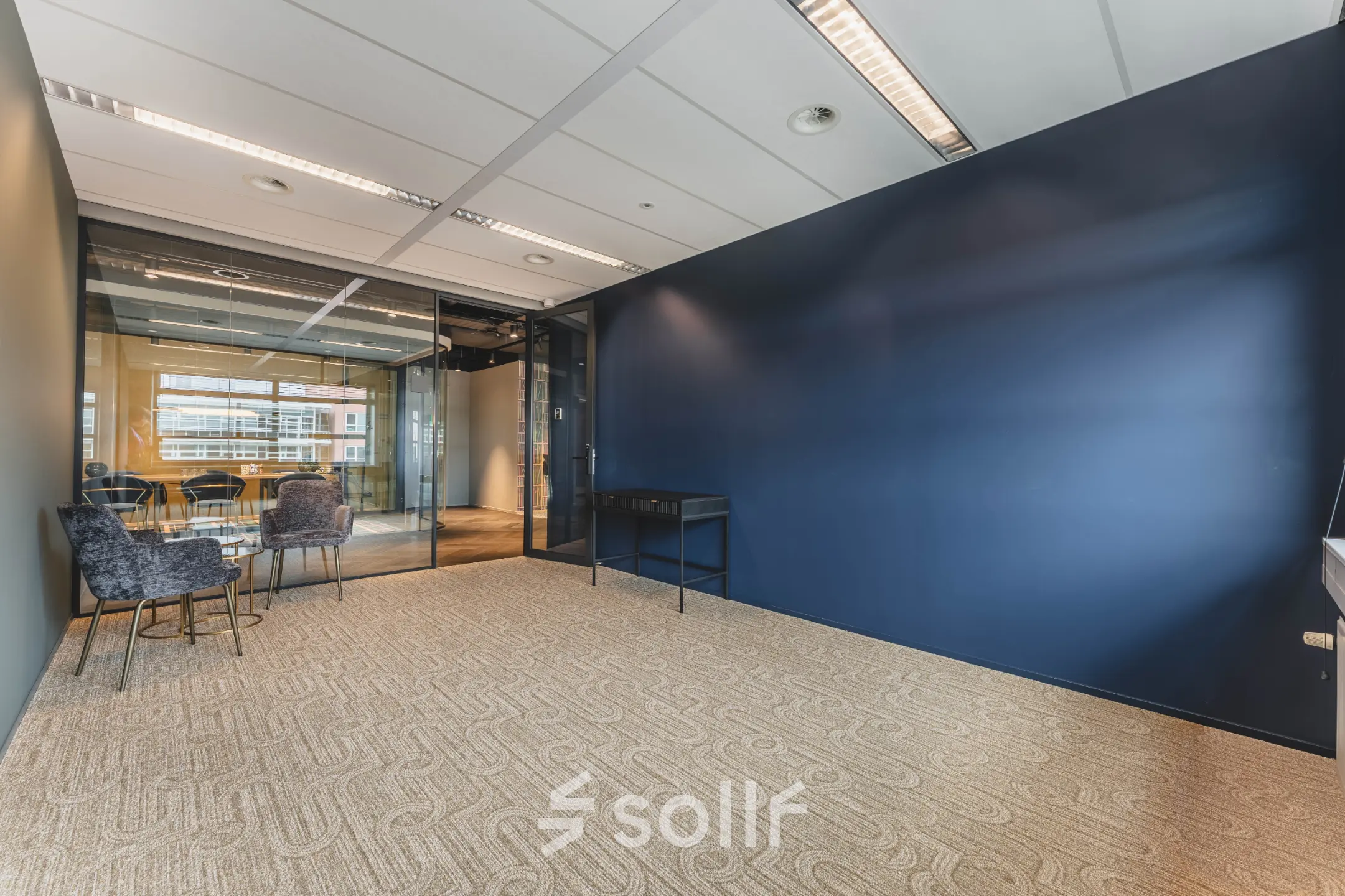 Contemporary office with blue accent wall at Rijnzathe 12, De Meern, offers a modern workspace for rent with glass-walled meeting room. Ideal for office space rental.
