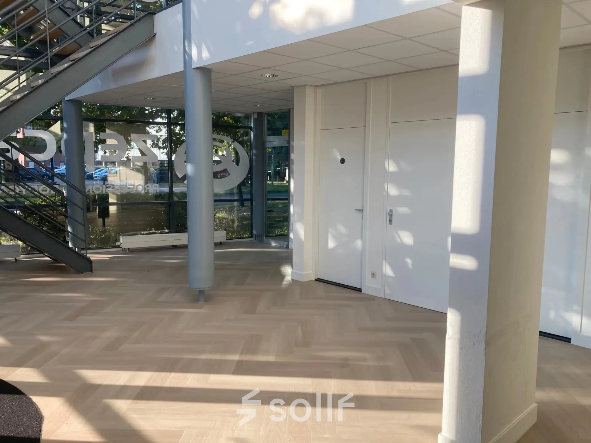 Interior of an office space at Delftechpark 17-19, Delft, showcasing a well-lit area with parquet flooring and a modern staircase, ideal for office space rental.