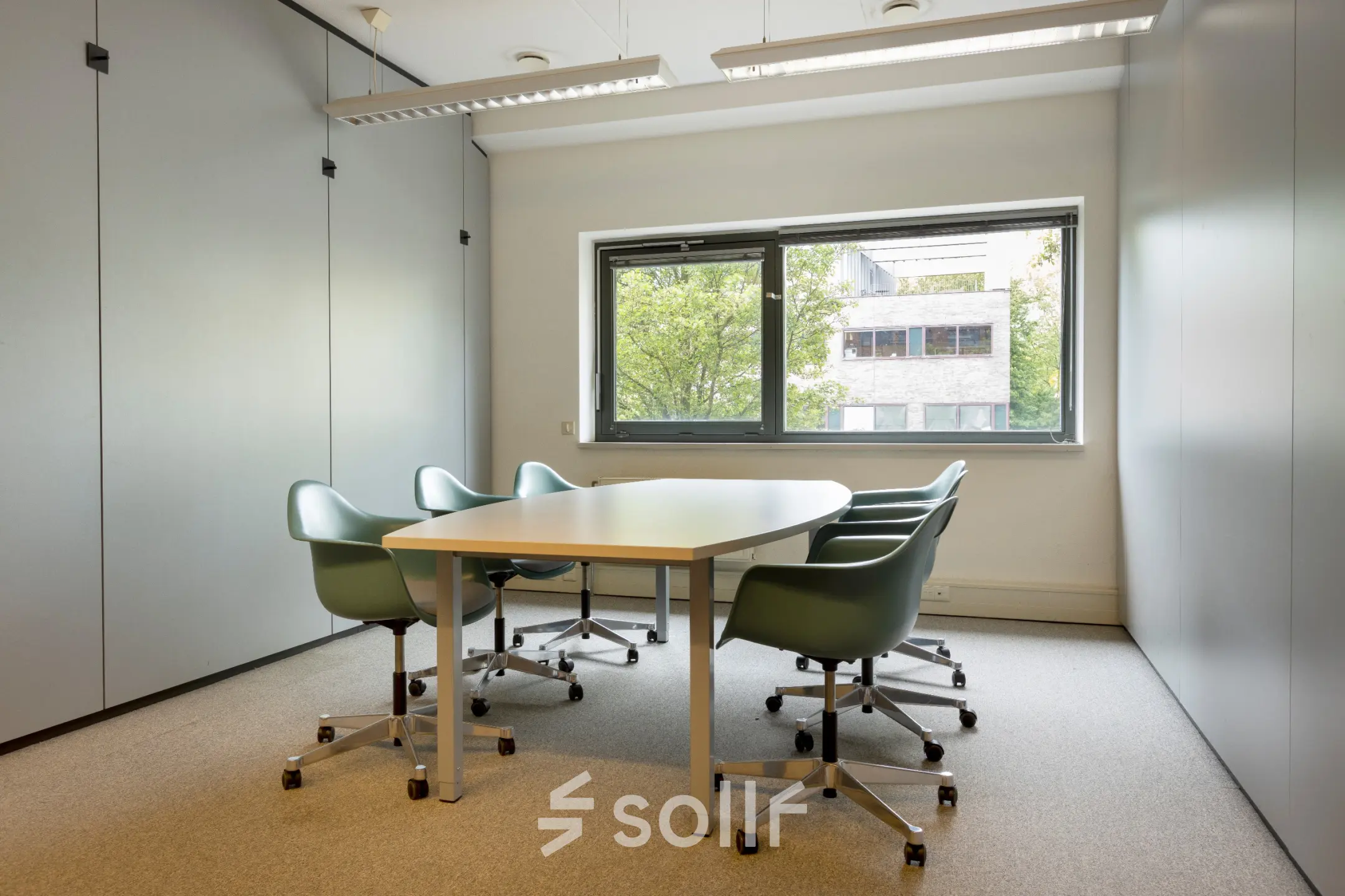 Light-filled office space for rent at Delftechpark 9, Delft, featuring a conference table with chairs and a clear view outside.
