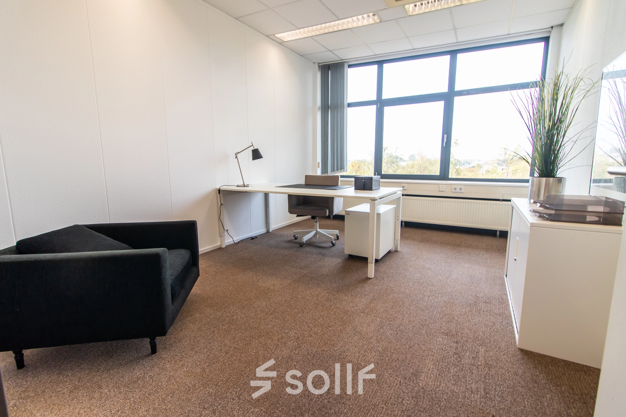 Bright office space to rent at Marshalllaan 2, Delft, featuring a desk and chair with large windows providing natural light. Ideal for office space rental.