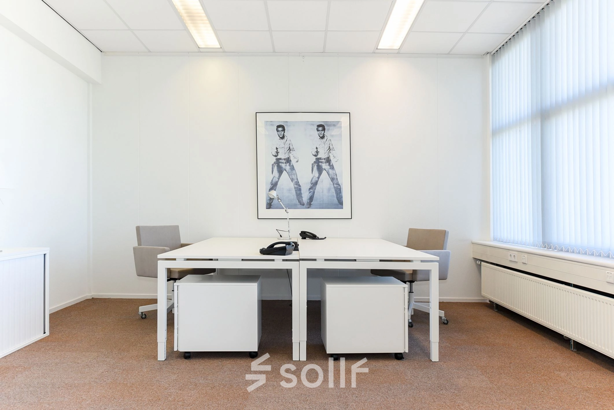 Bright office space for rent at Marshalllaan 2, Delft, featuring two white desks and chairs with a motivational poster on the wall.