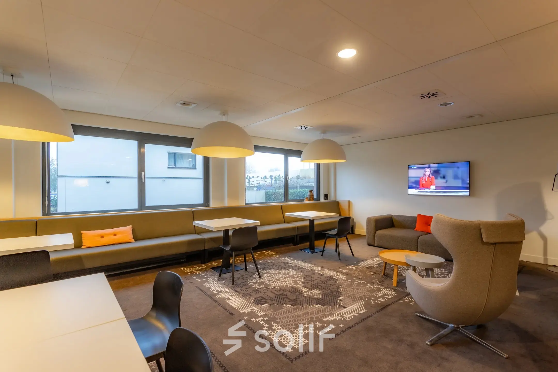Modern office space for rent at Marshalllaan 2, Delft, featuring cozy seating, tables, and a television, ideal for office space rental activities.