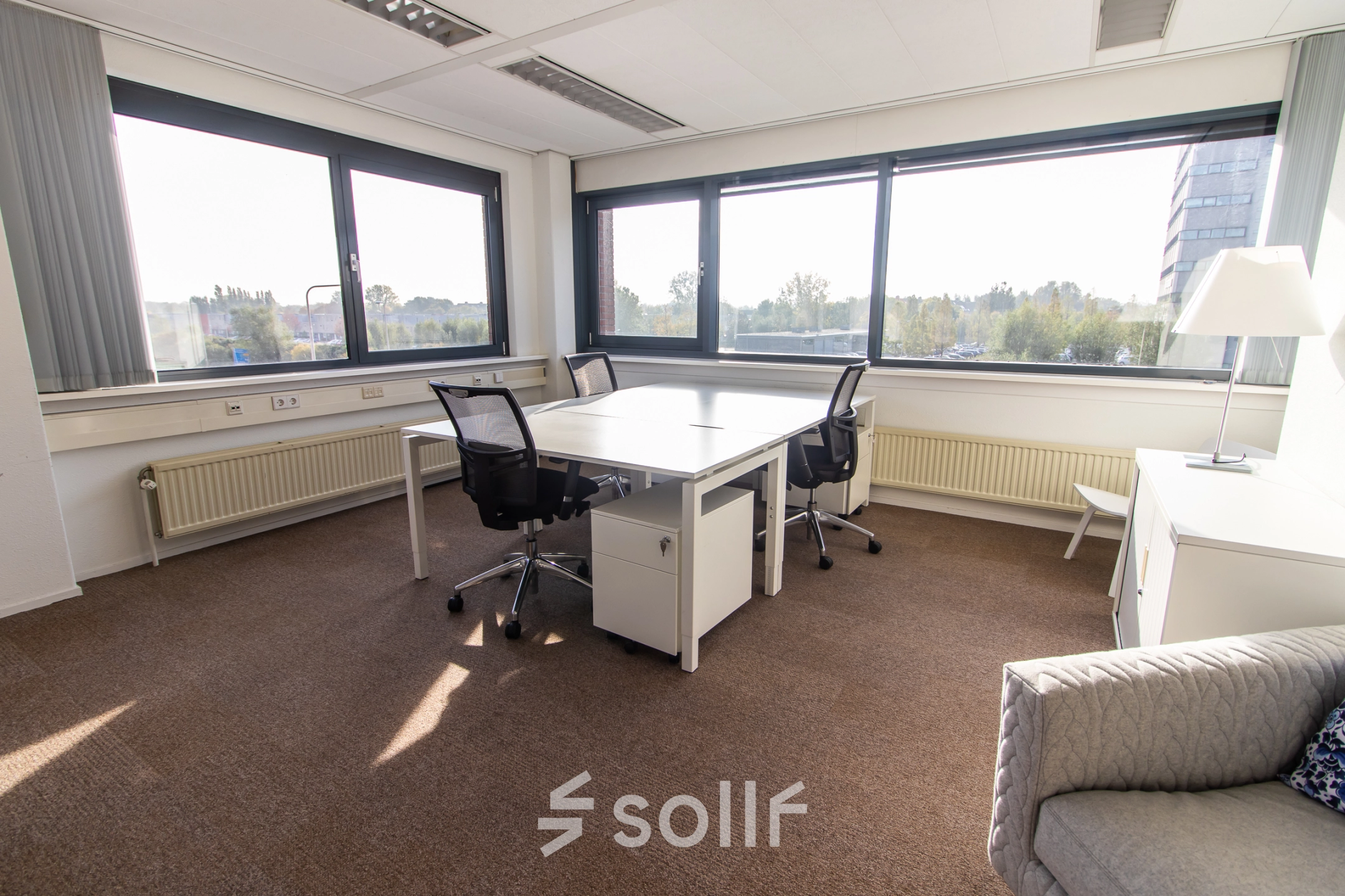 Bright office space at Marshalllaan 2, Delft, featuring large windows with a pleasant view, equipped with desks and chairs for rental office space needs.