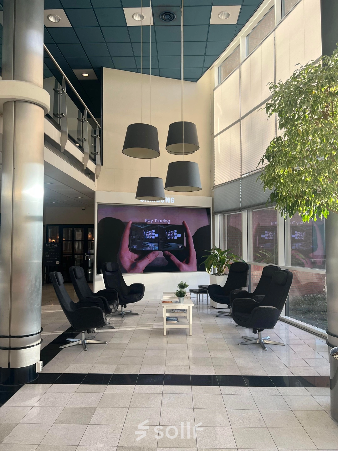 Modern lobby area with cozy black chairs, a small table, and large windows, perfect for office space rental at Olof Palmestraat 10, Delft.