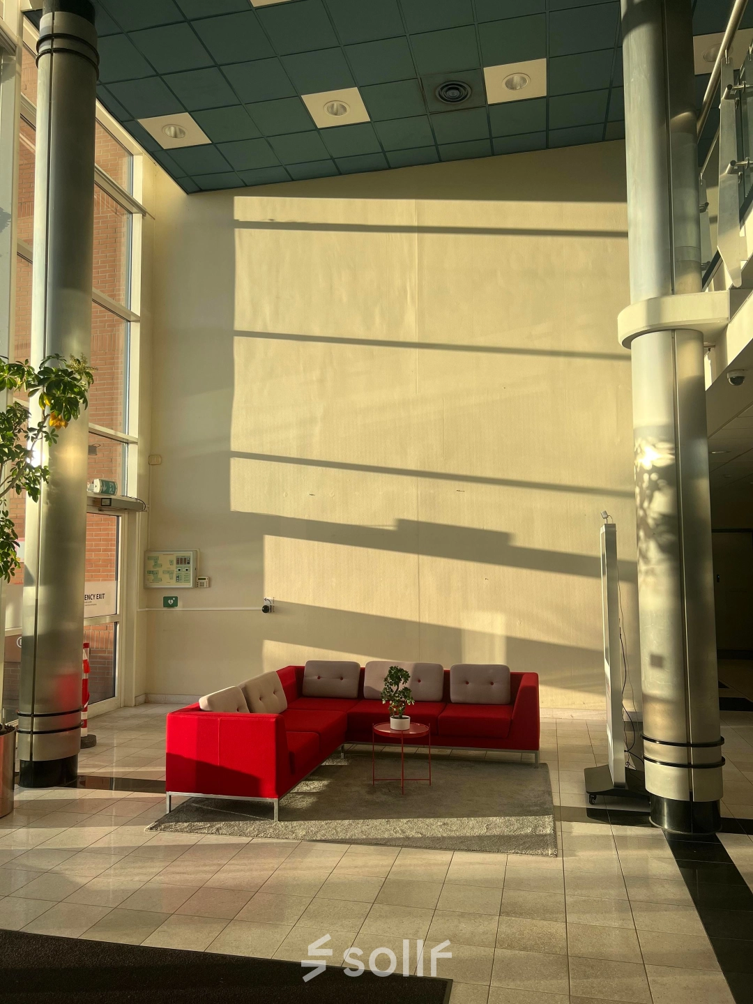 Bright office lobby at Olof Palmestraat 10, Delft with modern red seating and large windows, ideal for rent office space.
